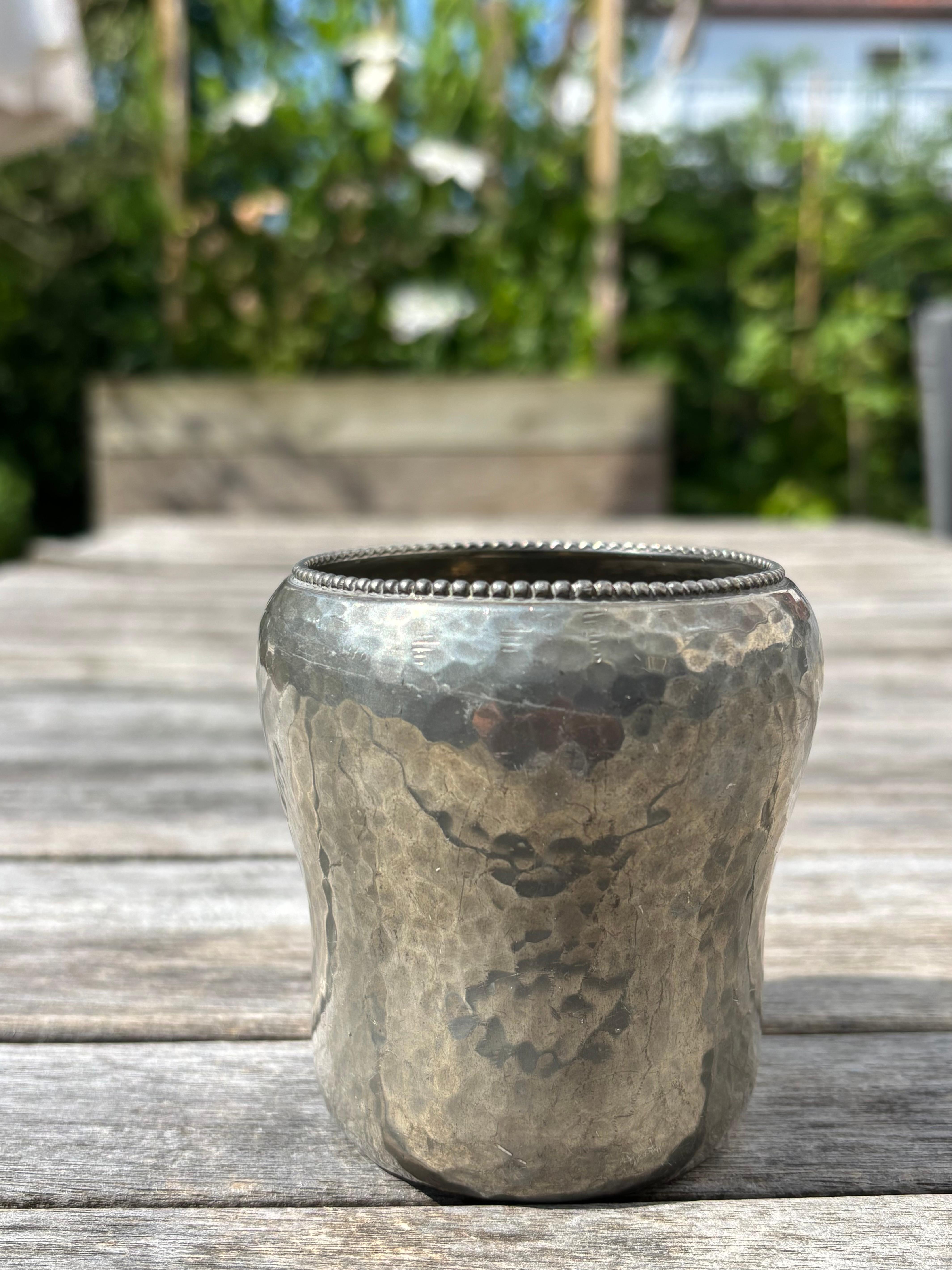 Vaso a coppa in peltro antico fatto a mano. Superficie simile all'argento martellato con piccole sfere che decorano il bordo superiore del pezzo dalla forma organica. 
Il timbro sotto la base recita: Dansk Haandarbejde Tin, che si traduce in: Peltro