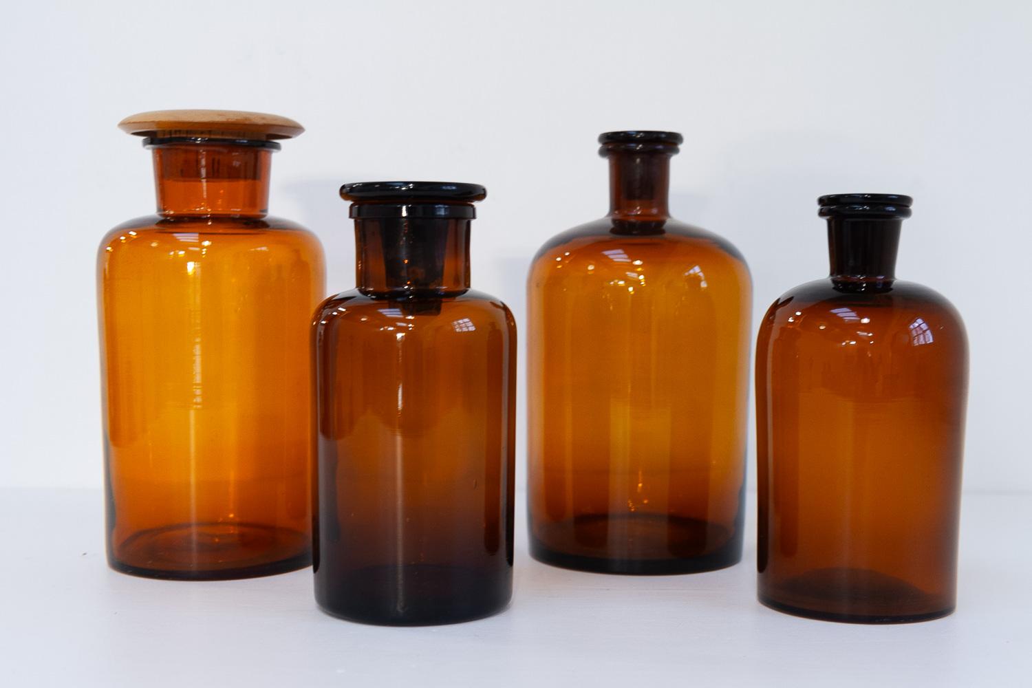 Anciens flacons en verre de pharmacie danoise, années 1900. Ensemble de 4.

Ensemble de quatre flacons d'apothicaire soufflés à la main en verre ambré brun/doré avec bouchons.

Taille des bouteilles : 
Diamètre 12,5 cm, hauteur  26 cm
Diamètre 13 cm