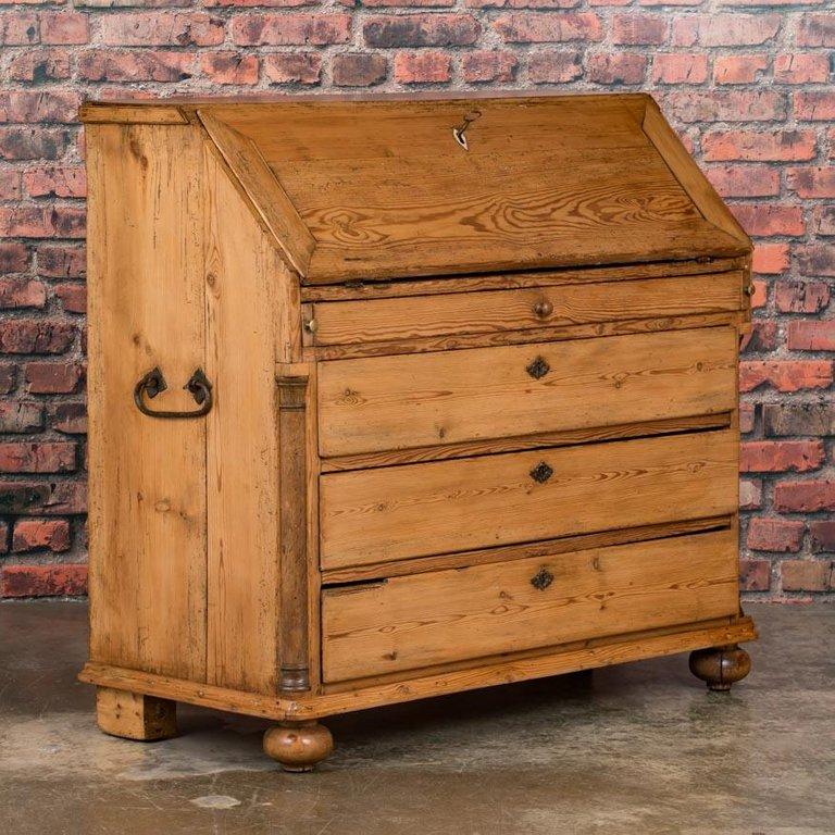 This Danish circa 1860 pine breakfront bureau / desk features simple lines and is fully functional.

The desk interior is fitted with a number of small drawers with matching brass knobs, and a center compartment with a hinged door, along with