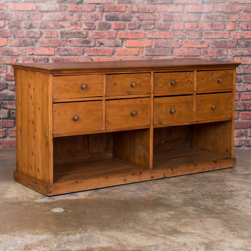 Unique and versatile, this antique pine cabinet was made to be viewed from all sides, with cut panels on the back. Originally used as a grocer's store counter, the eight drawers offer ample storage, making for the perfect kitchen island or