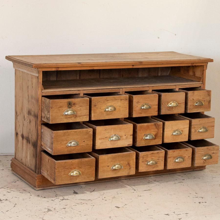 Fun and function abound in this free standing pine kitchen island with 15 drawers. This delightful pine cabinet originally served as a grocer's shop counter or storage cabinet. Counters similar to this were used throughout shops in the European
