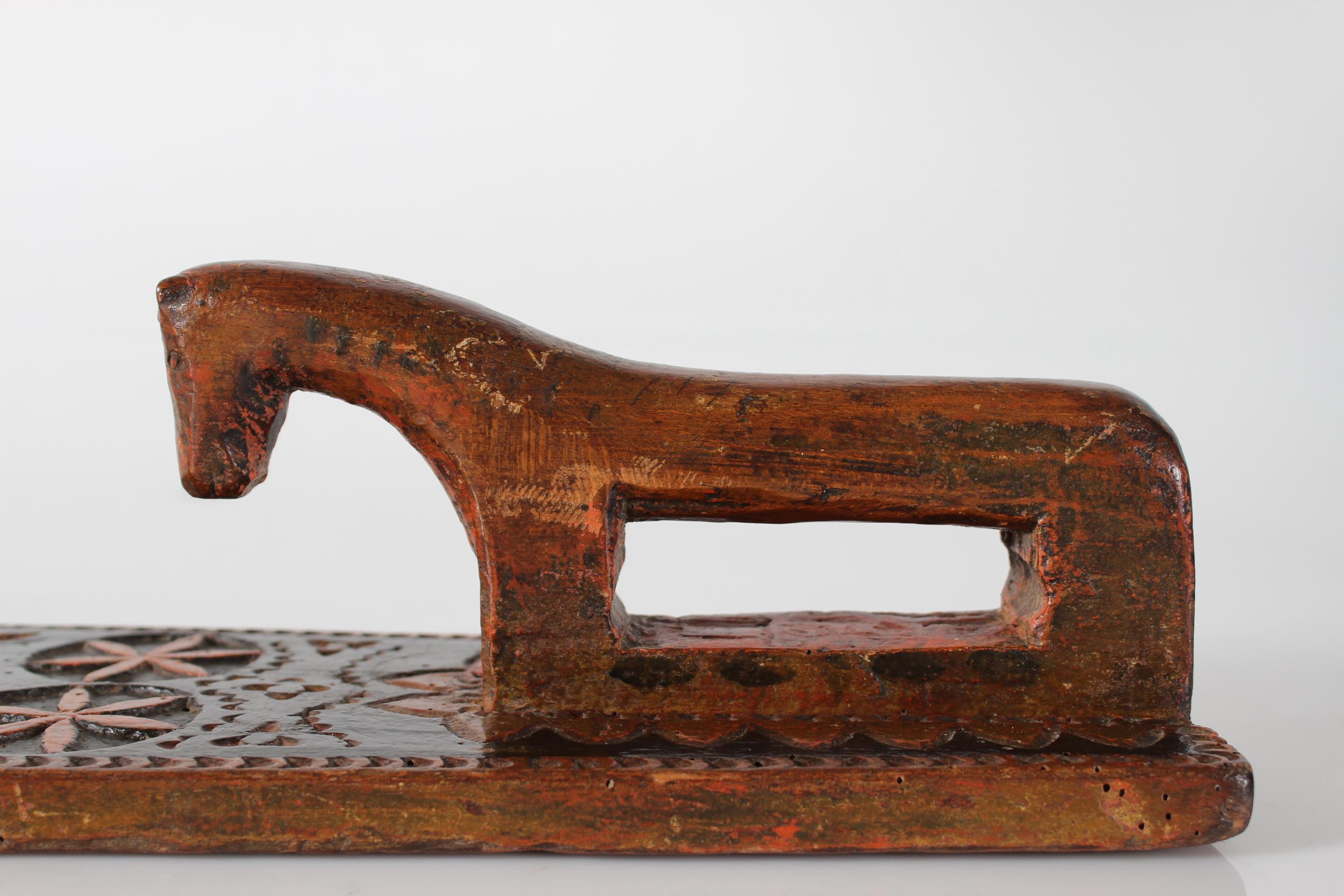 Danish mangle board (clothing and bedding press) dated 1791.

Made of wood richly decorated with hand-carved geometric patterns and a horse as handle. With traces of original brown and maroon paint.
The decoration also shows initials A.J.D ?. and