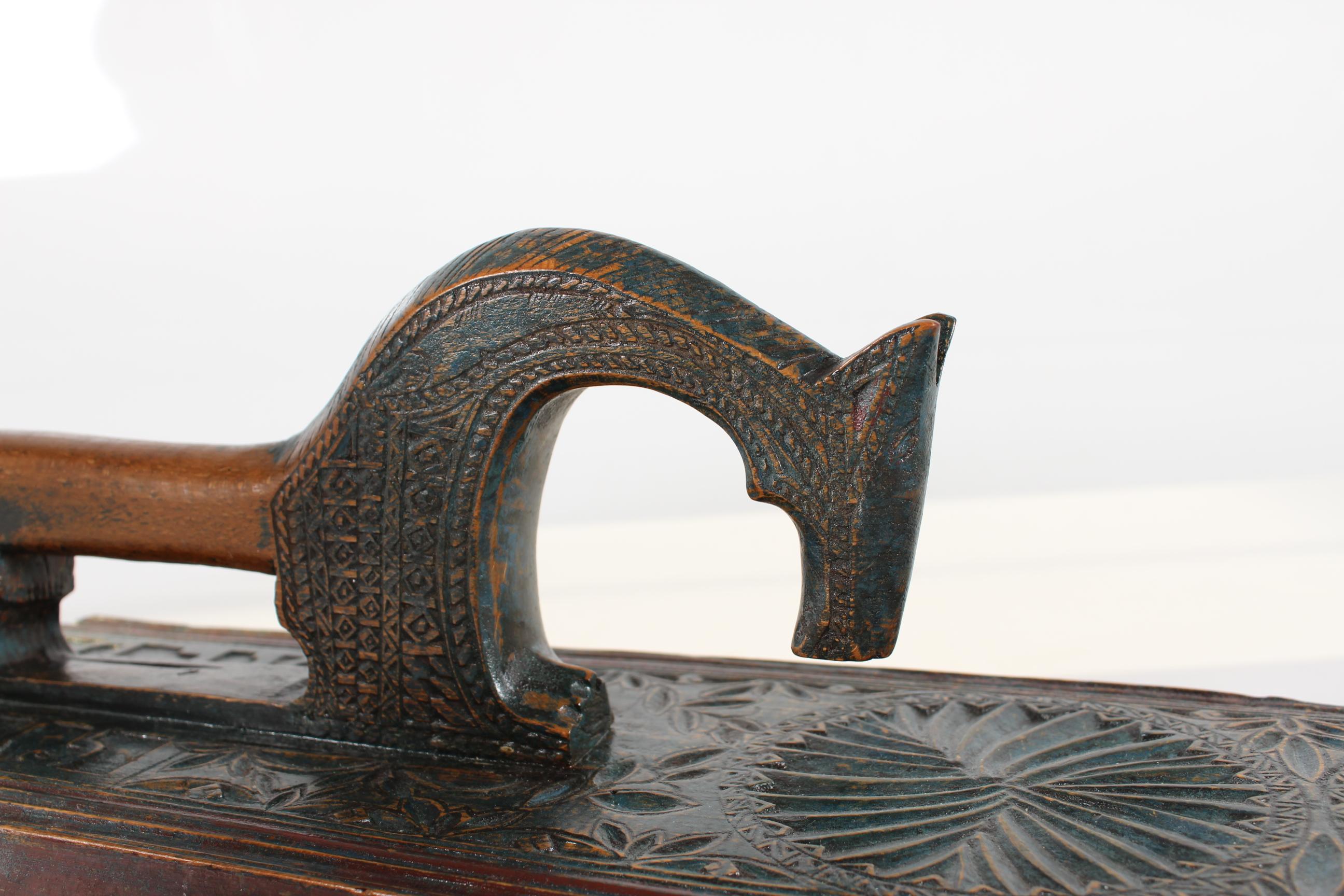 Danish mangle board (clothing and bedding press) dated 1815.

Made of wood richly decorated with hand-carved geometric patterns and a horse as handle. With traces of original blue and maroon paint.
The decoration also shows initials A.L.D. and the