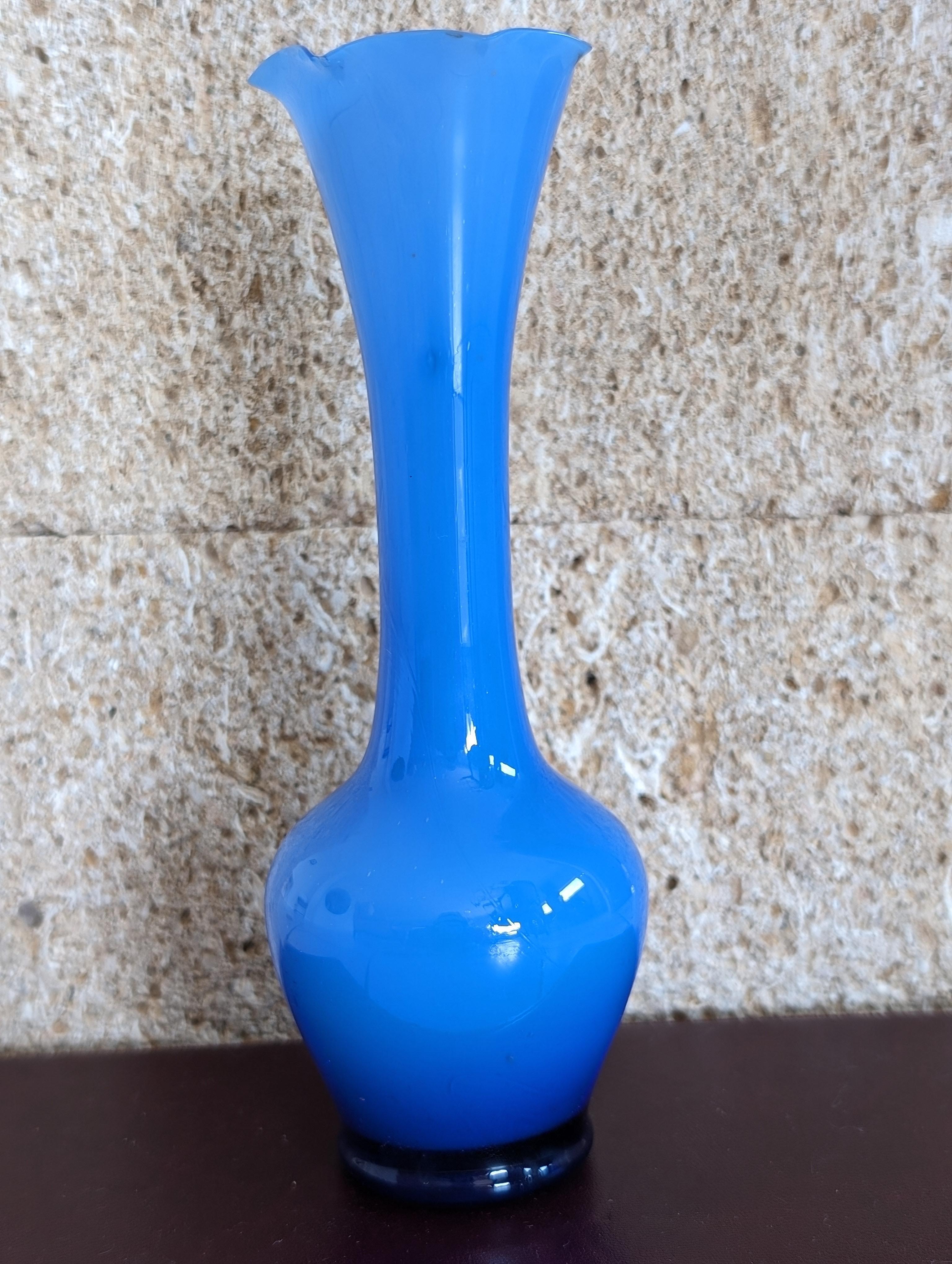 Ti presentiamo uno splendido vaso opalino blu scuro della metà del XX secolo, un pezzo accattivante che incarna un'eleganza senza tempo e un fascino vintage. Questo squisito vaso mette in mostra le ricche e profonde sfumature del vetro opalino blu