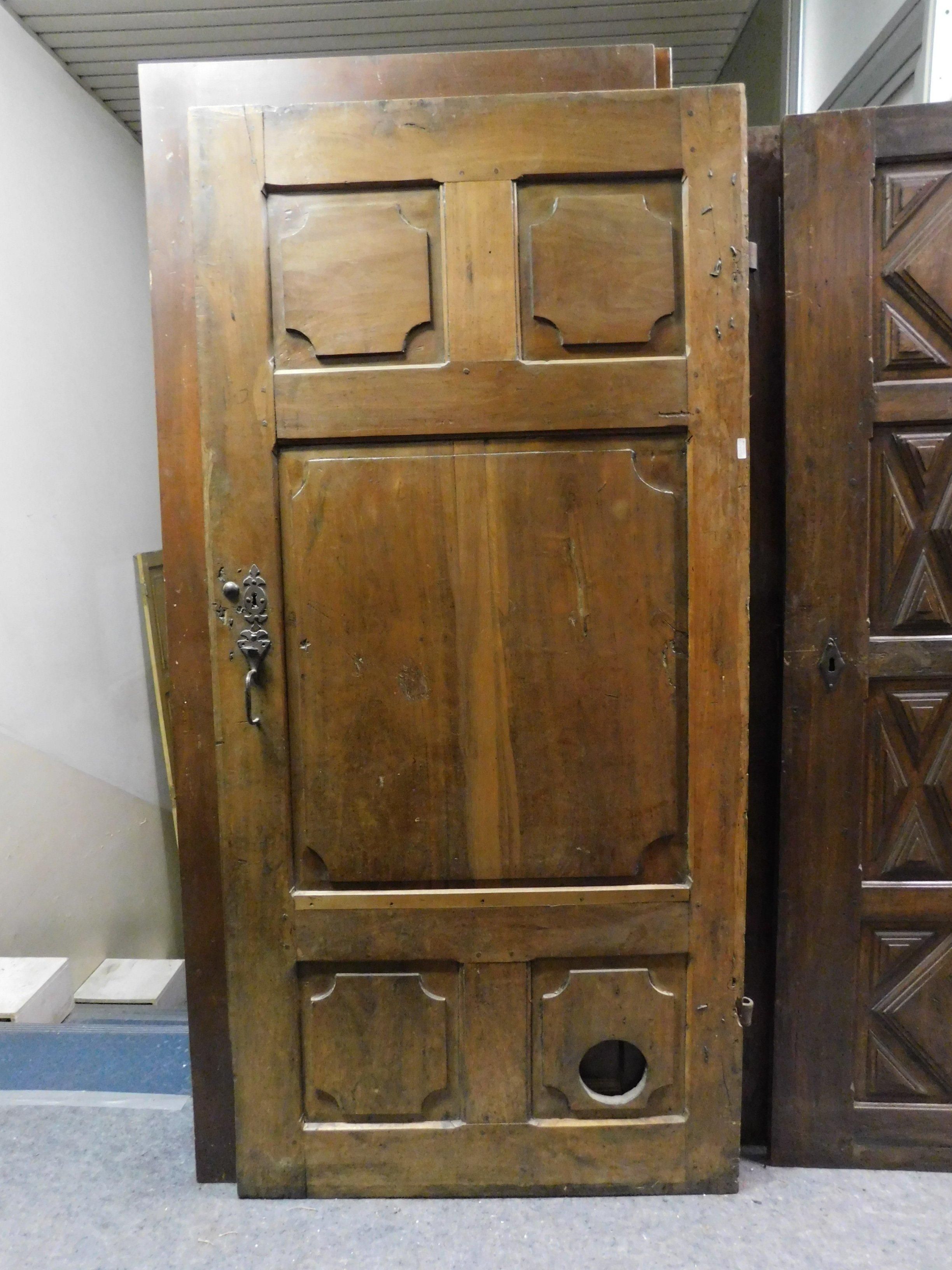 Antigua puerta marrón oscuro típica de madera muy dura, paneles tallados a mano y muy buen estado de conservación, aún con los hierros originales, fabricada en el siglo XVIII en Italia.
En la parte inferior de la puerta, puedes ver el agujero para