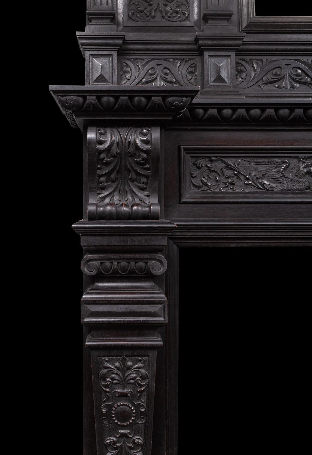 An antique English Jacobean revival oak mantlepiece with original dark finish. This tall and well proportioned wooden fireplace with original bevelled glass mirror is profusely carved with various Jacobean Renaissance style carvings.

  