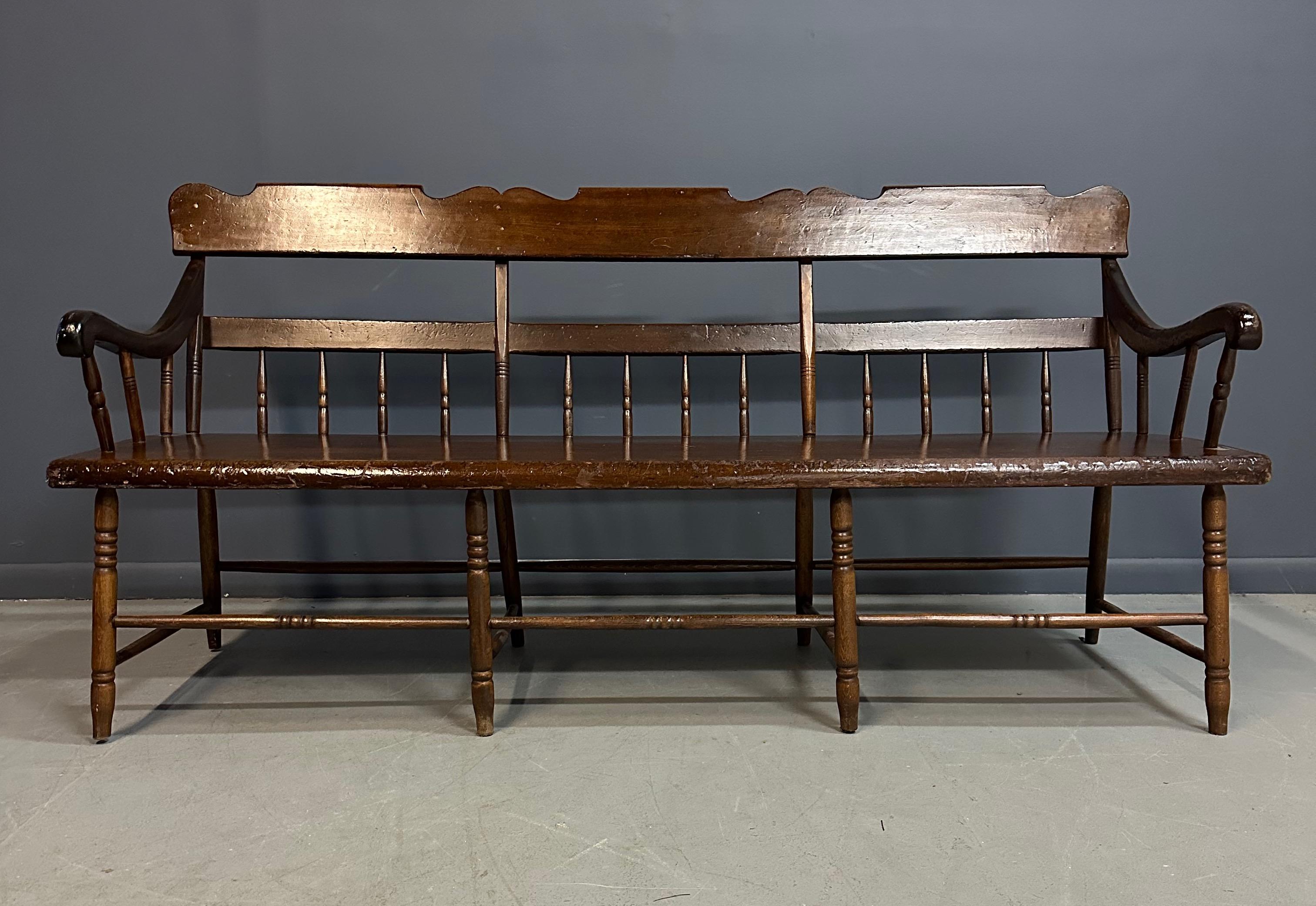 Crafted from pine, this antique Deacon's bench boasts a rustic aesthetic with its spindle back design. Its size makes it perfect for use as a statement piece in a foyer, mudroom, or covered porch. Elevate your home decor with this beautifully