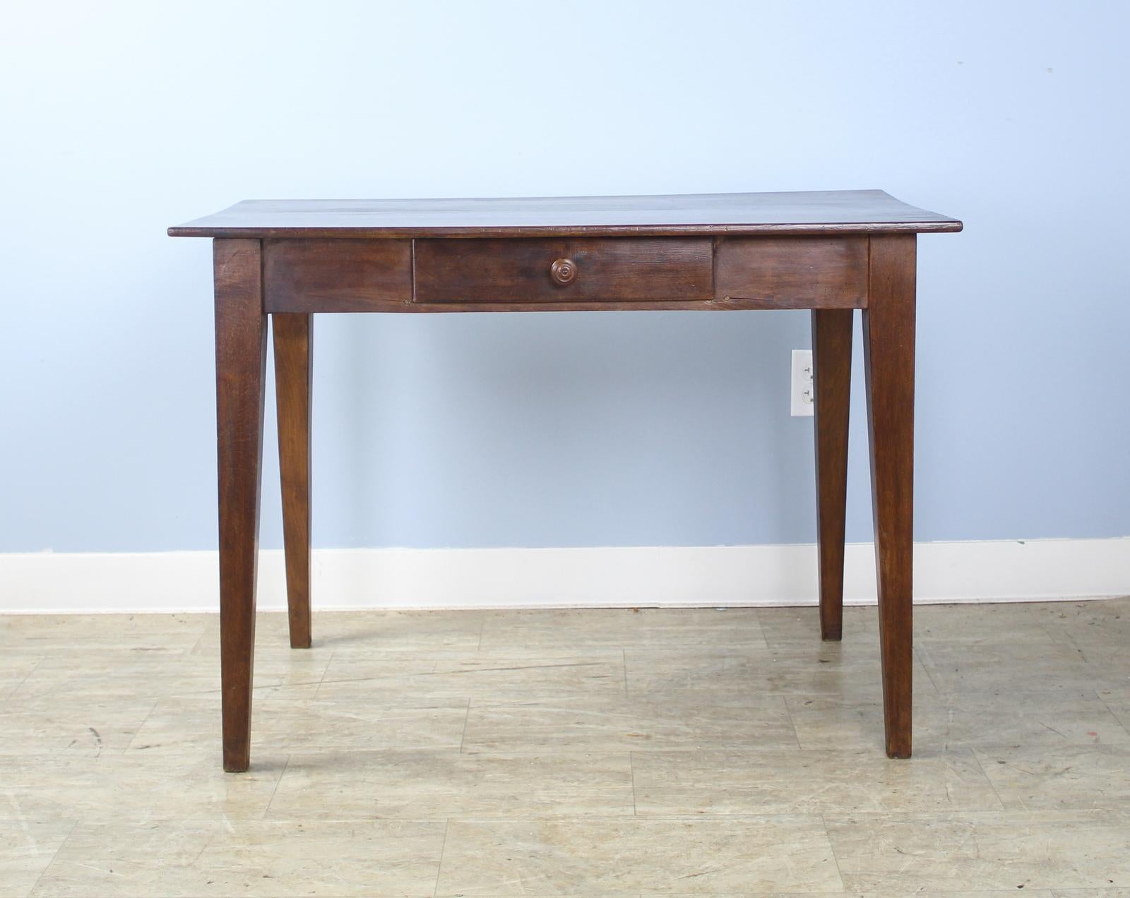 An elegant dark pine side table or small writing table with nice grain and patina. Classic tapered legs and a single center drawer. 23.75 inch apron height is good for knees.