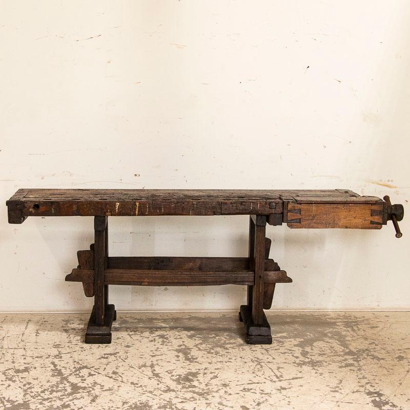 Workbenches such as this are often used as console or sofa tables today. The depth of dark patina on this particular work table comes from years of constant use. It has one wooden vice and a recessed tray where the carpenter would lay his tools. The