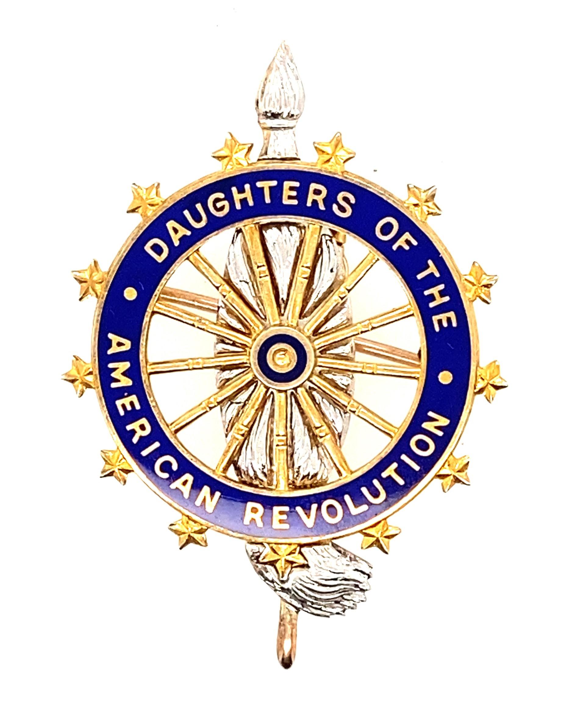 In its original embossed box, this 14k gold circa 1901-1909 brooch/pendant bears the emblem of the Daughters of the American Revolution. A spinning wheel with 13 spokes, representing the 13 original colonies, features 