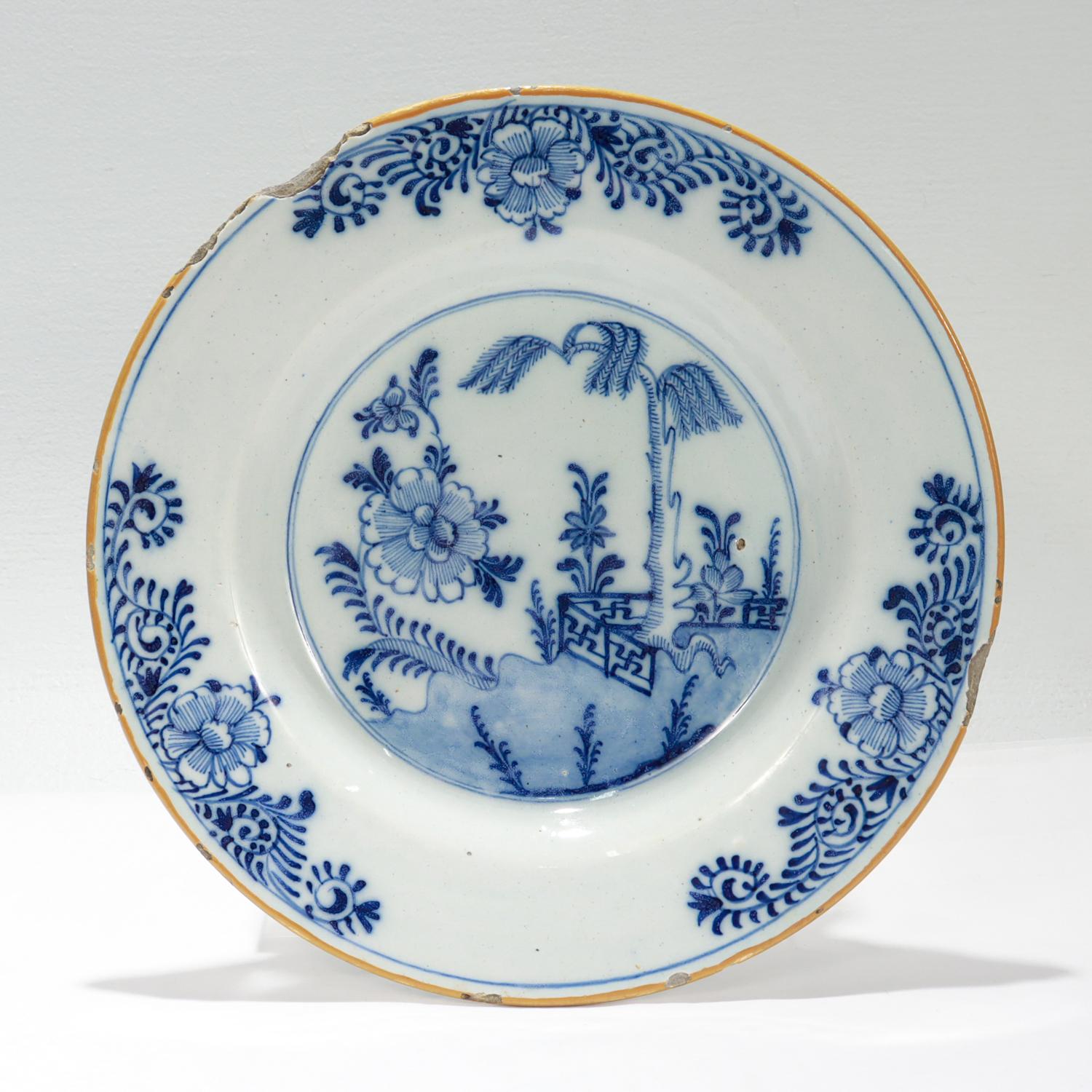 Plato antiguo de cerámica holandesa de Delft.

Junto a la fábrica De Porceleyne Bijl (El Hacha de Porcelana). 

Con un borde ancho y plano y un pozo poco profundo.

El pozo está decorado en azul bajo vidriado con una escena de jardín chino que