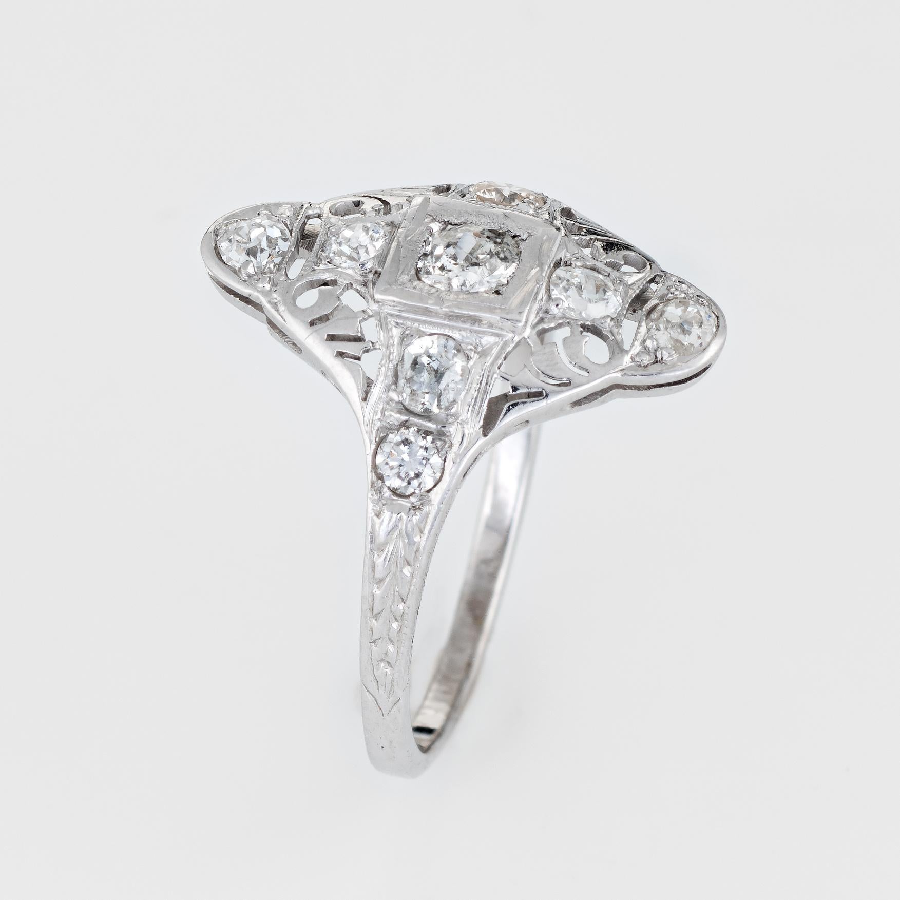 Finely detailed vintage Art Deco era ring (circa 1920s to 1930s) crafted in 18k white gold. 

Nine old mine cut diamonds total an estimated 0.60 carats (estimated at I-J color and SI2-I1 clarity). 

The ring features a lacy filigree design with an