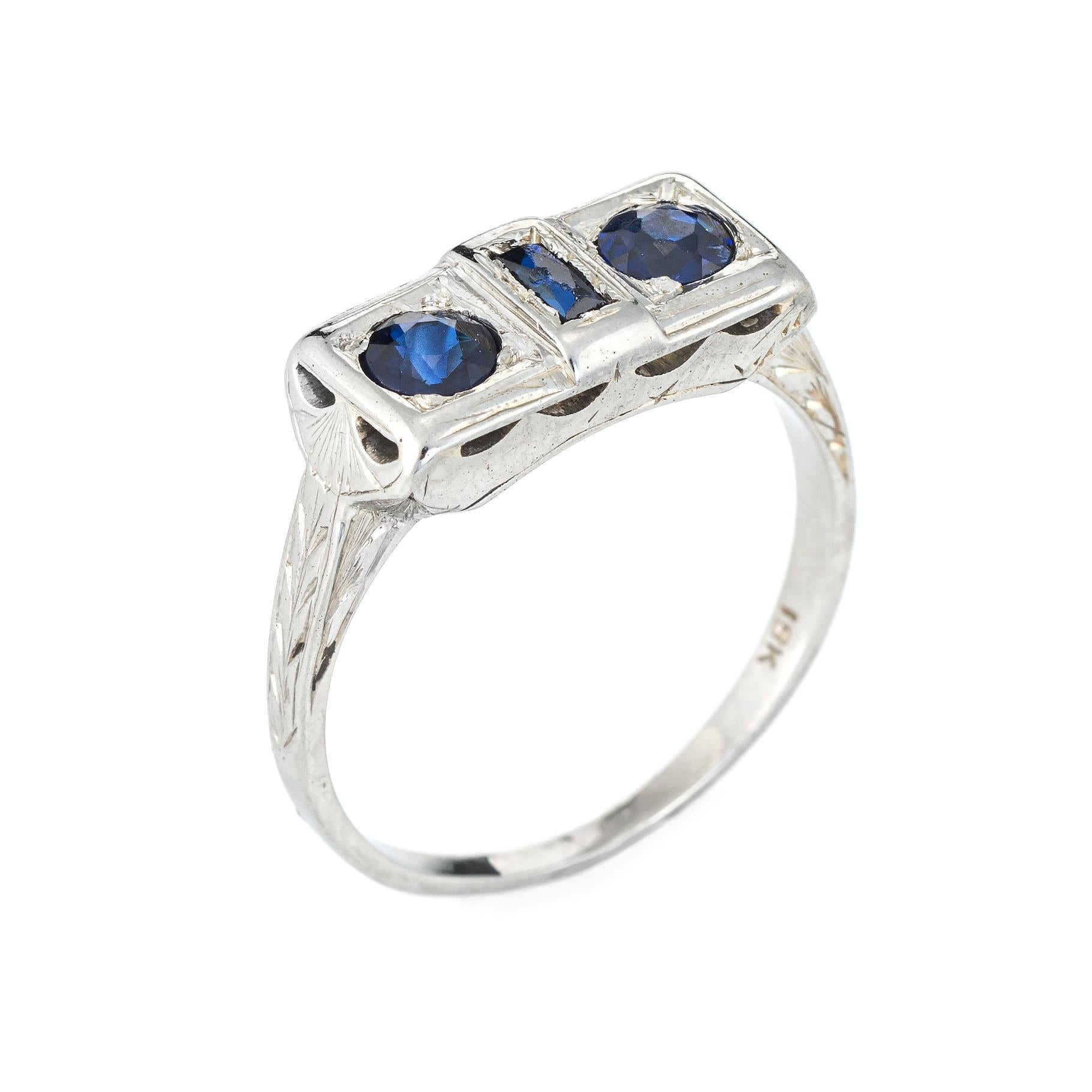 Finely detailed vintage Art Deco era ring (circa 1920s to 1930s) crafted in 18 karat white gold. 

Two faceted round cut sapphire are estimated at 0.15 carats each, accented with one estimated 0.05 carat French cut sapphire. The total sapphire