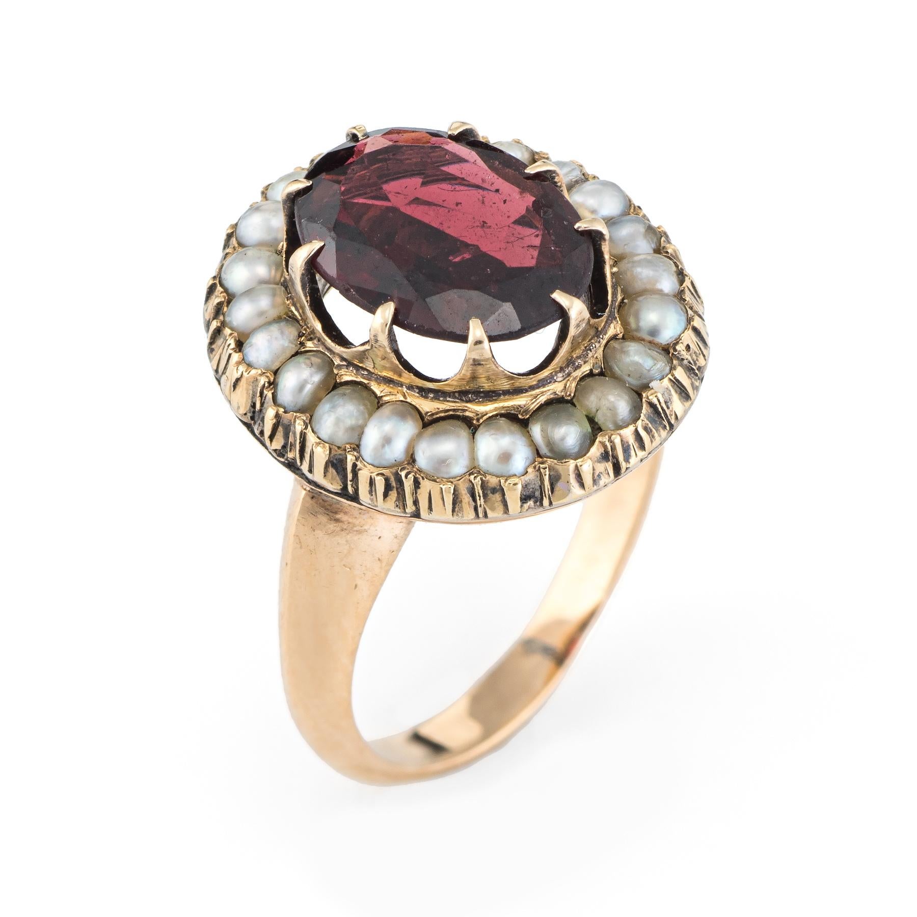 Elegant & finely detailed Art Deco era ring (circa 1920s to 1930s), crafted in 14 karat yellow gold. 

Faceted oval shaped garnet measures 10mm x 6.5mm (estimated at 2 carats). 22 natural seed pearls surround the garnet and measure (average) 2mm.