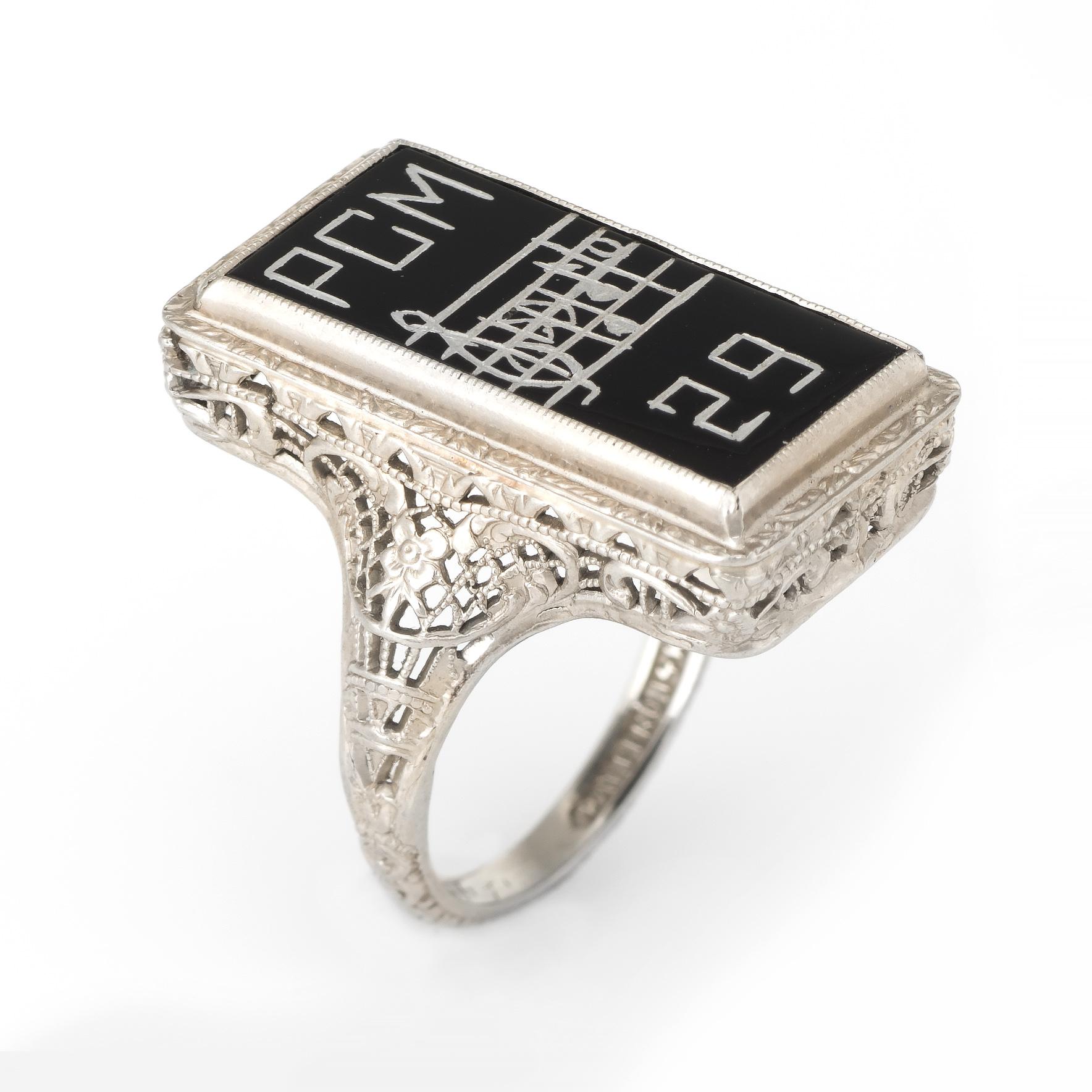 Finely detailed vintage Art Deco era ring (circa 1920s), crafted in 14 karat white gold. 

Onyx is inscribed 'PCM' along with a music sheet and the year '29'   

Lacy filigree mount with embossed floral detail, a hallmark of the Art Deco era.  

The