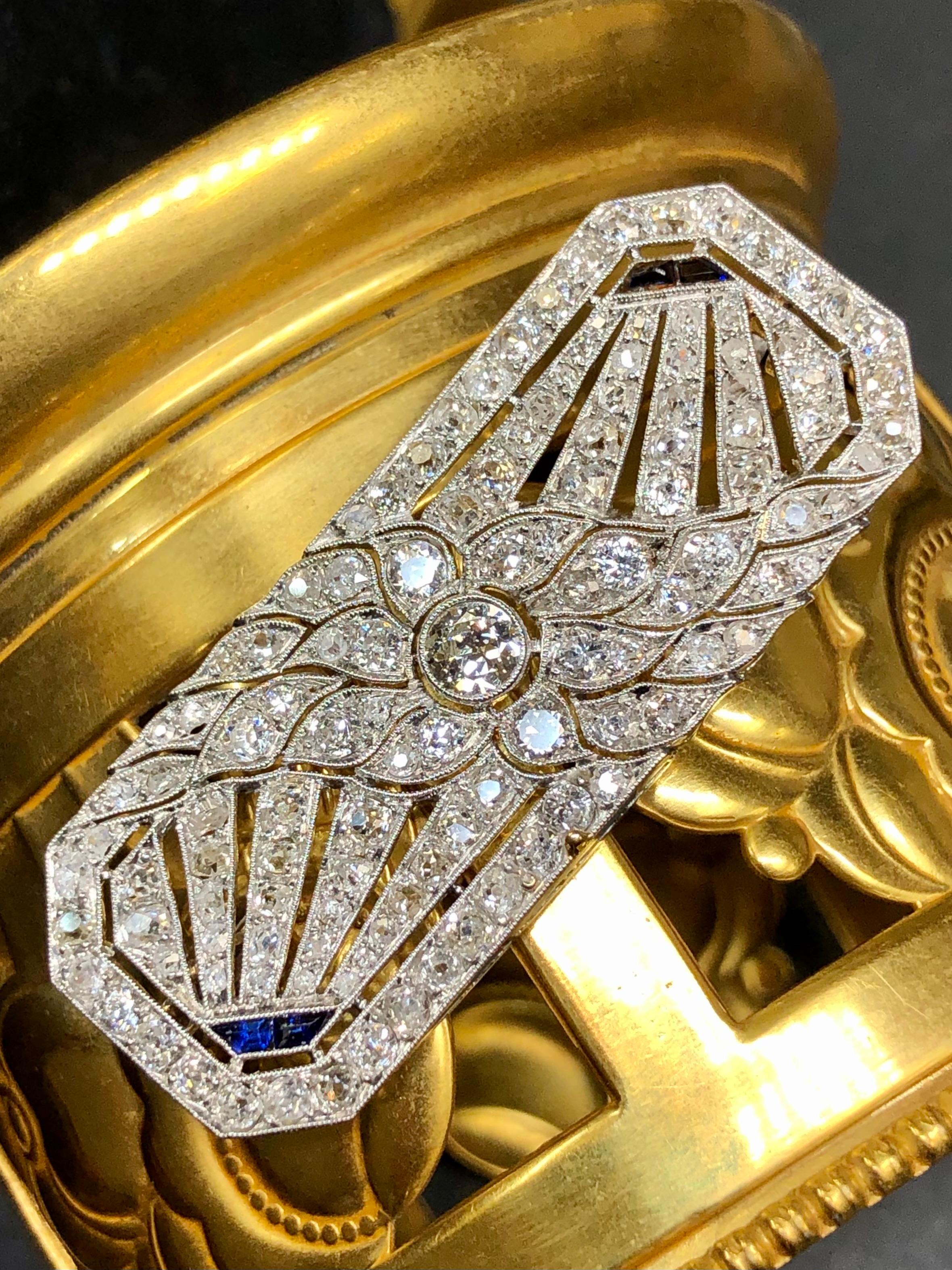 An exquisite piece of jewelry history. This early Art Deco brooch has been hand crafted in platinum and set with approximately 4.50cttw in G-I color Vs clarity old mine cut and rose cut diamonds as well as calibrated sapphires. Large central stone