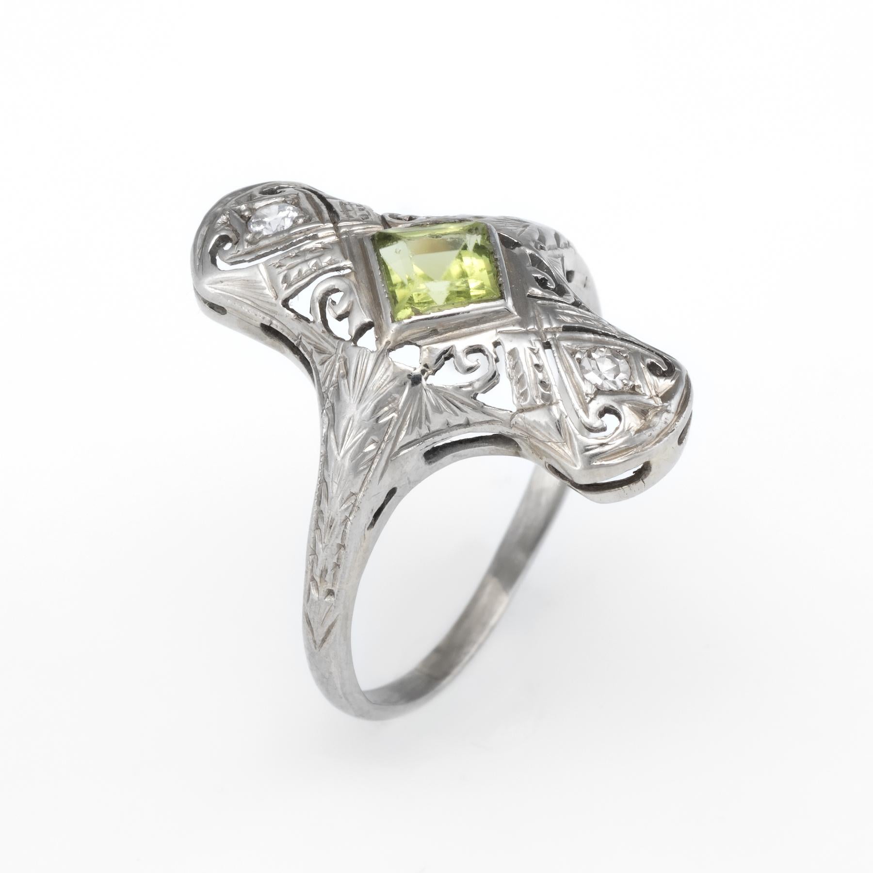 Finely detailed vintage Art Deco era ring (circa 1920s to 1930s), crafted in 14 karat white gold. 

Centrally mounted estimated 0.80 carat peridot is accented with two estimated 0.02 carat diamonds (0.04 carats total estimated weight - estimated at