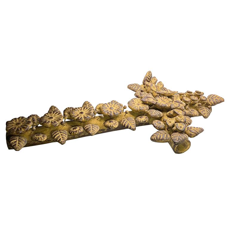 Une croix antique ornée, faite à la main, avec des motifs floraux, de papillons et de feuilles. Le motif présente une série de fleurs et de feuilles en relief et texturées, disposées symétriquement le long des bras de la croix, ce qui lui confère un