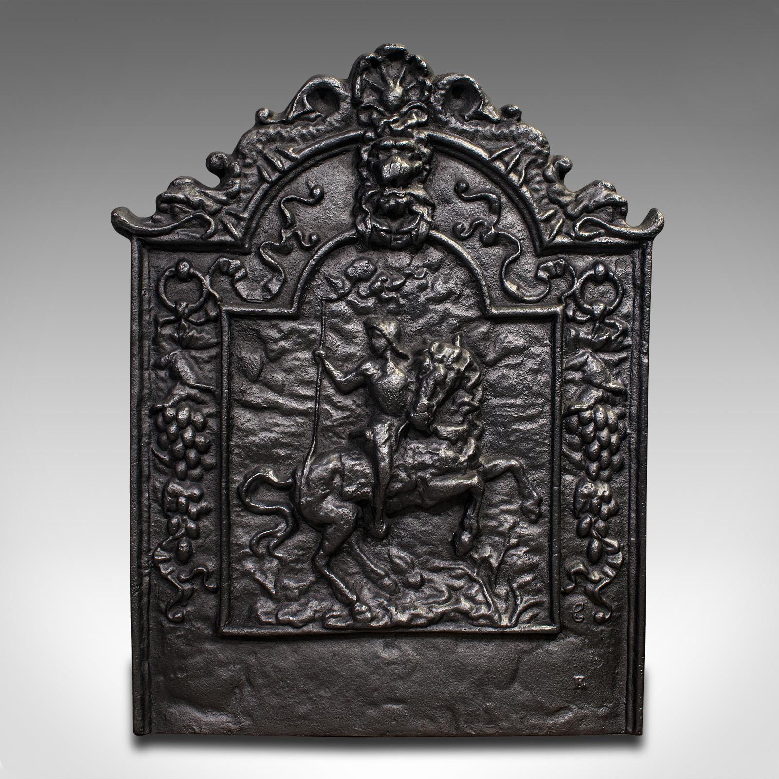 This is an antique decorative fire backrest. An English, cast iron fireplace back, dating to the Victorian period, circa 1900.

Charming cast, depicting a mounted rider and old English icons
Displays a desirable aged patina and in good