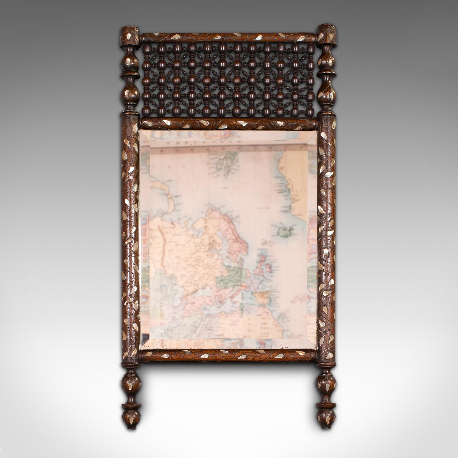 This is an antique decorative wall mirror. An Indian, mahogany and glass colonial mirror, dating to the late Victorian period, circa 1900.

Of unusual form and decorative finish
Displaying a desirable aged patina throughout
Select stocks accentuated