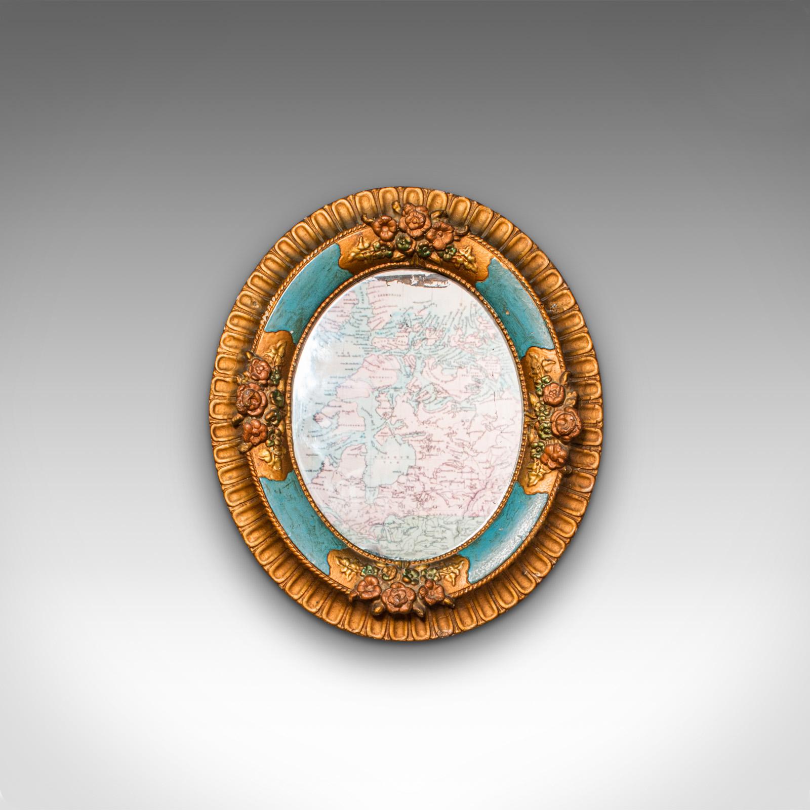This is an antique decorative wall mirror. A German, plaster and gilt finished oval mirror in the manner of the Black Forest, dating to the late Victorian period, circa 1900.

Pleasingly expressive and colorful form with Black Forest