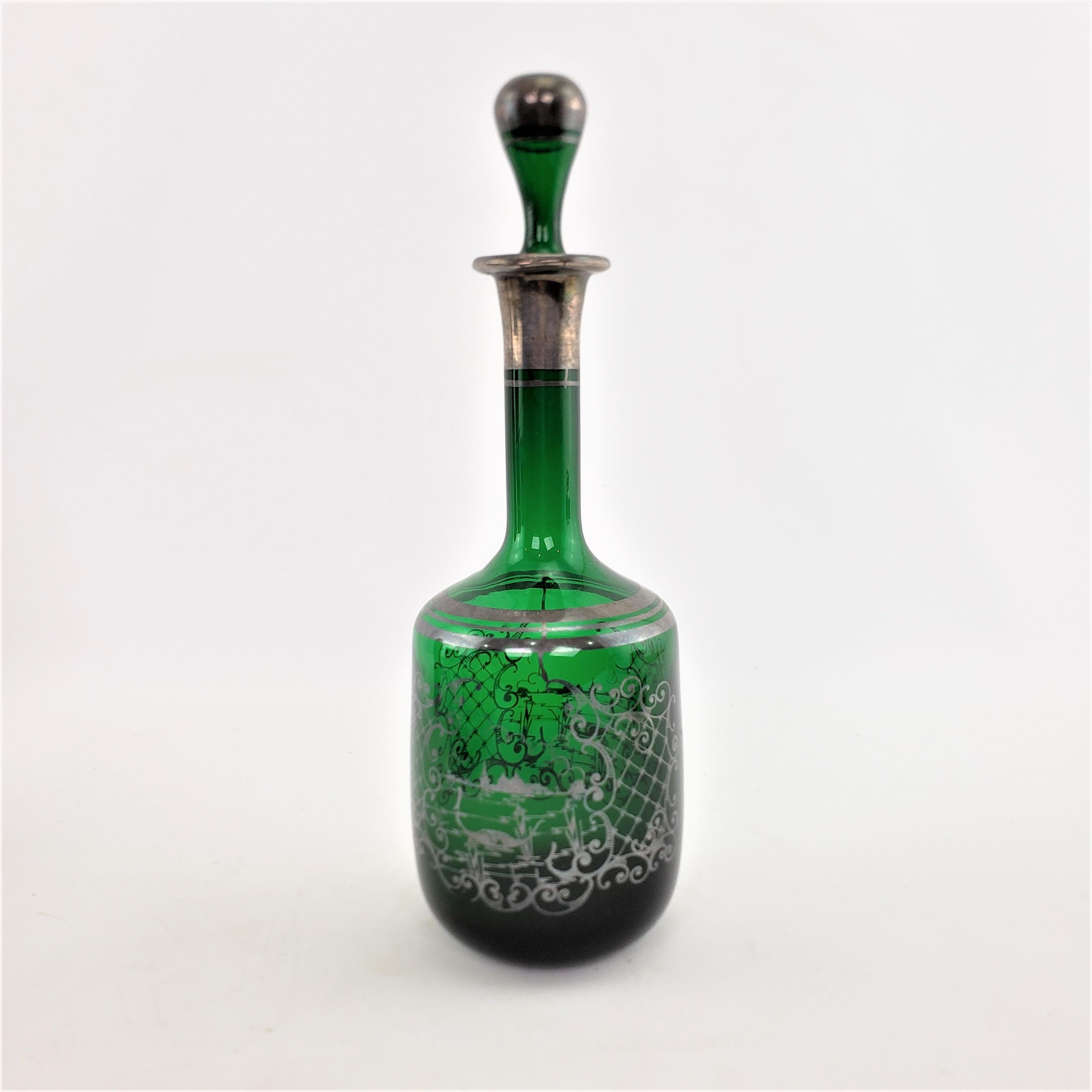 This antique bottle decanter is unsigned, but presumed to have been made in France in approximately 1920 in an Art Deco style. The decanter is done in a deep green glass with silver overlaid decoration in two identical pond vignettes framed in a