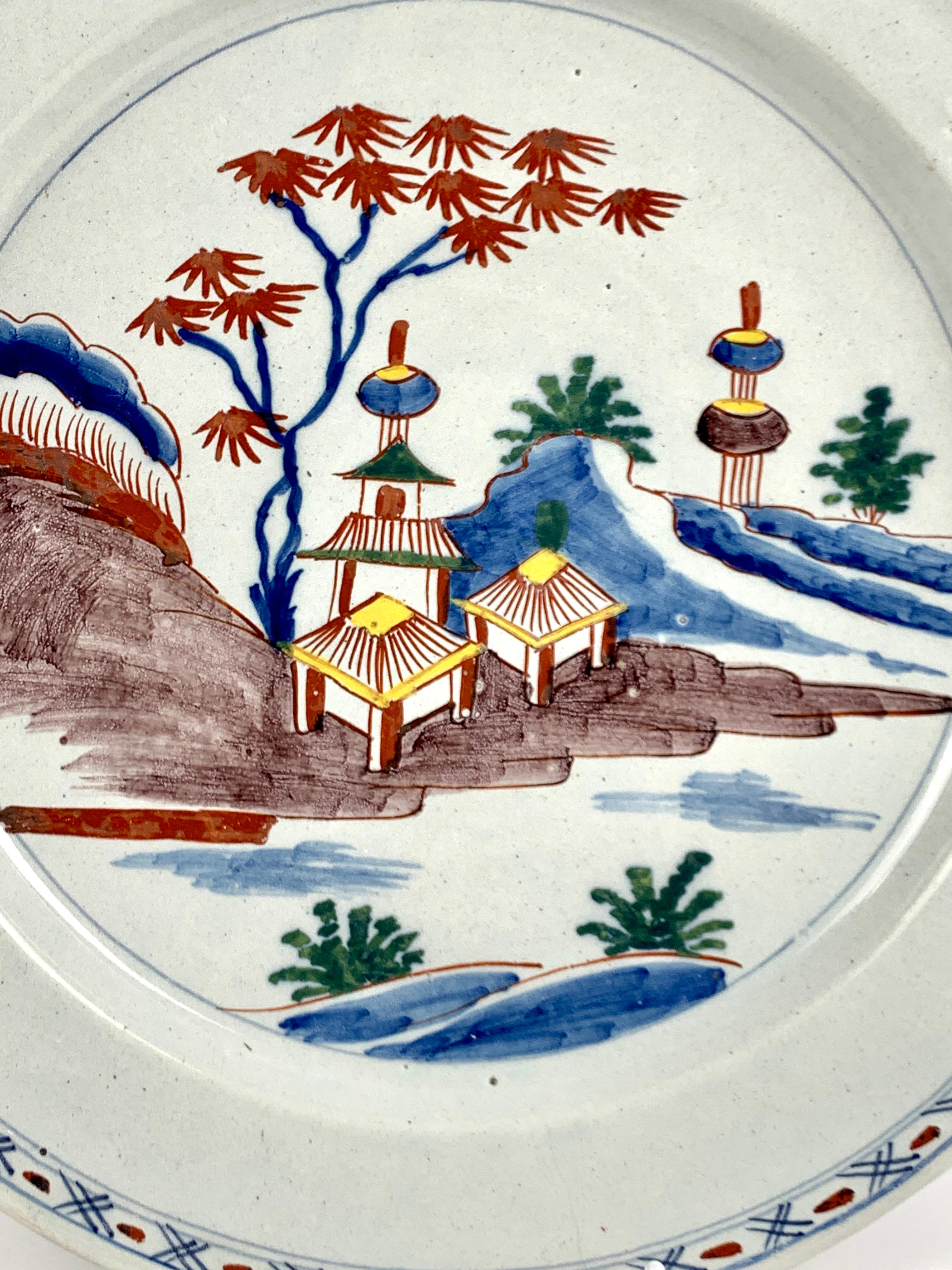 This antique Dutch Delft charger was hand painted in the 18th century, circa 1770.
The center of this large Dutch Delft charger shows a lovely chinoiserie scene painted in vibrant polychrome colors, including blue, green, yellow, purple, and iron