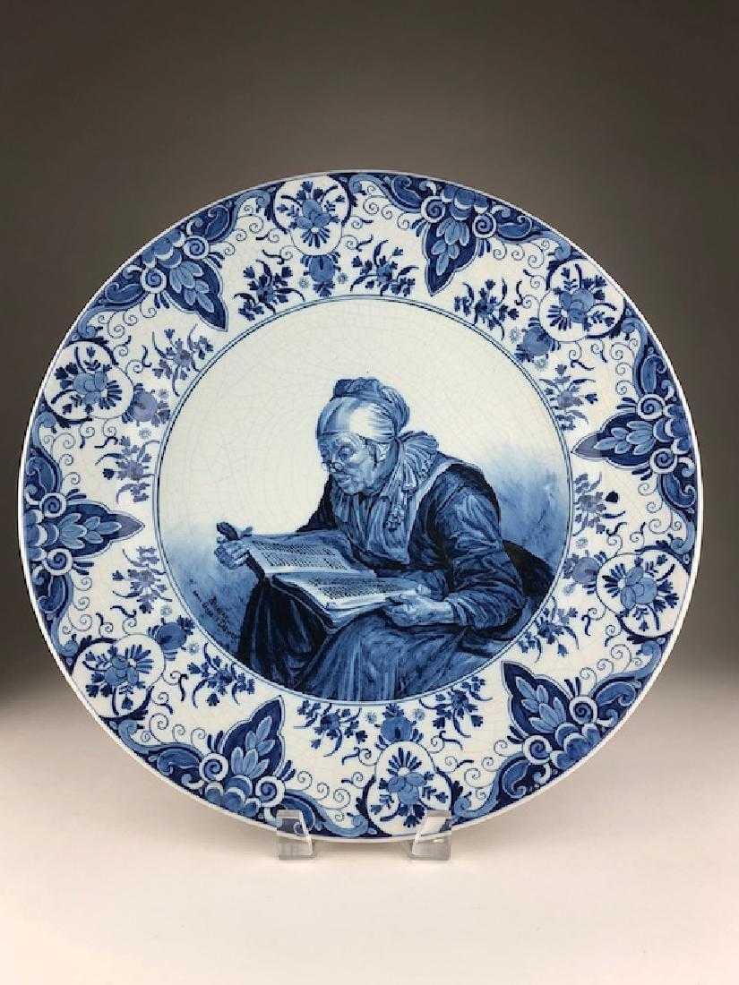 Delft porcelain charger, Holland.
An old woman reading from a tattered book.
Signed 