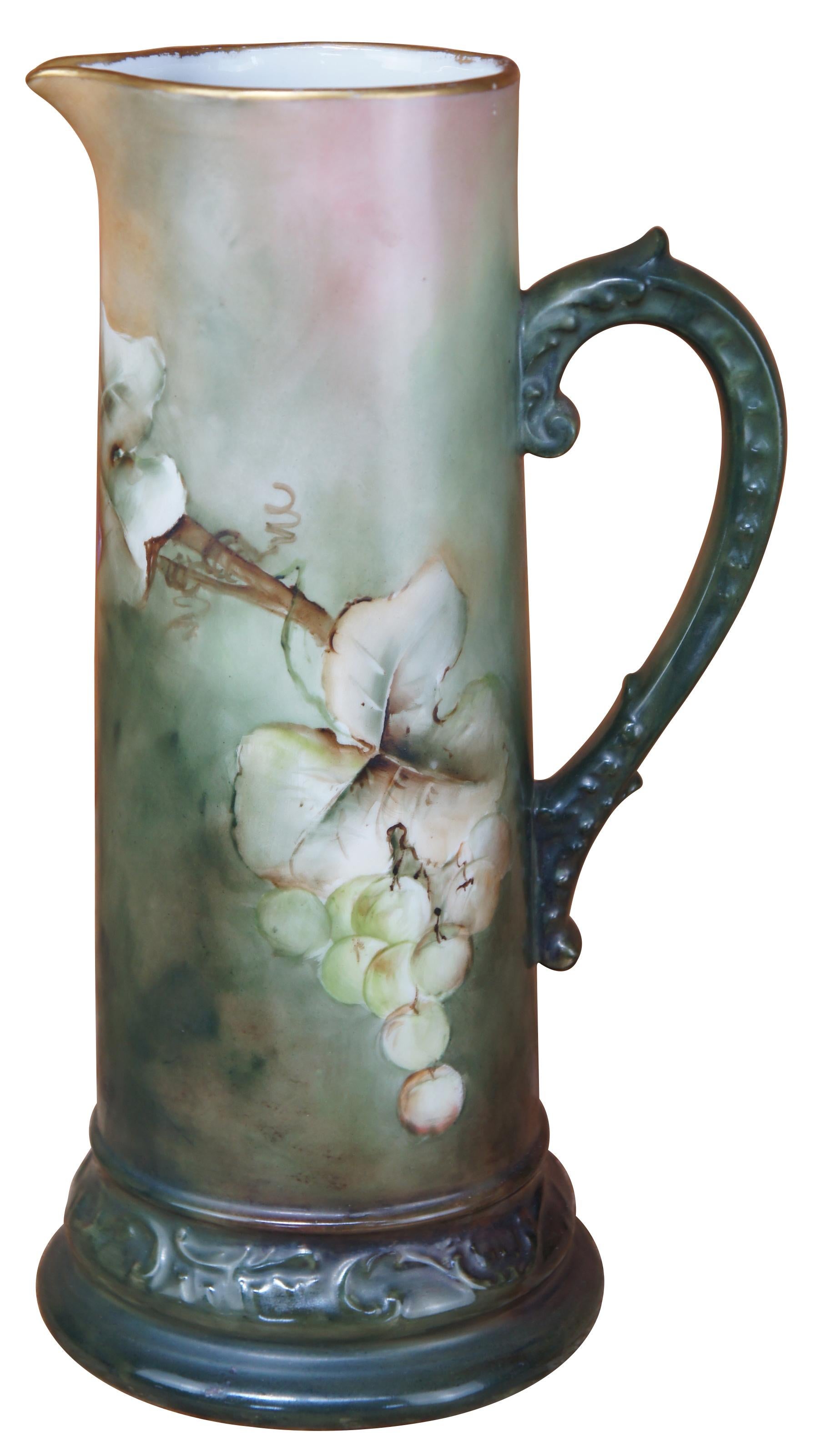 This antique tankard was made around the turn of the century in France. Features beautiful hand painted grapes over a earthy green color. The upper lip has gold trim. An exquisite piece of craftsmanship. Don't miss the opportunity to add this beauty