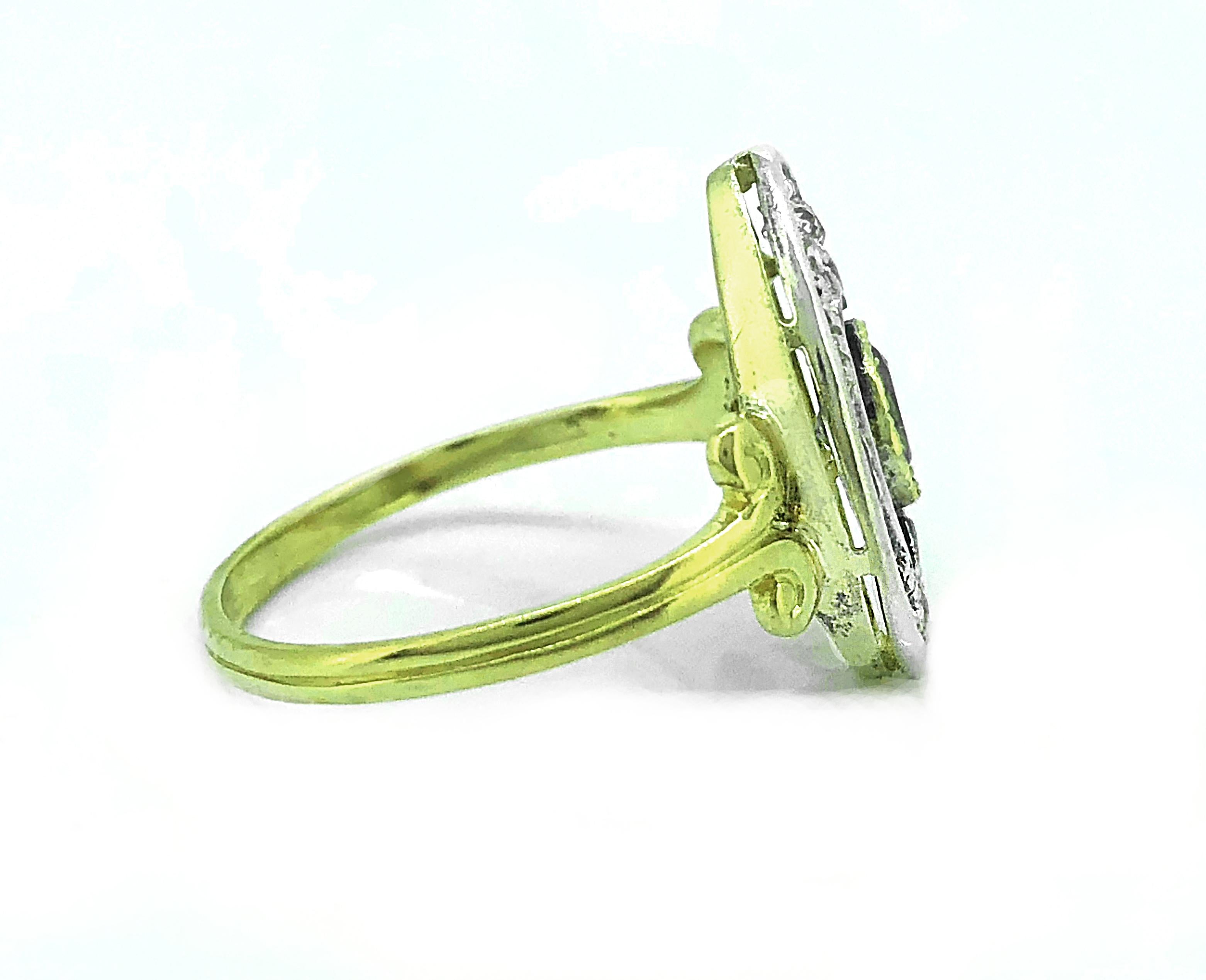A hard to find Edwardian Antique demantoid garnet and diamond fashion ring featuring a stunning natural green demantoid garnet (apx .60ct) displaying strong diamond like fire and electric green color. The ring is accented with .20ct. apx. T.W. of