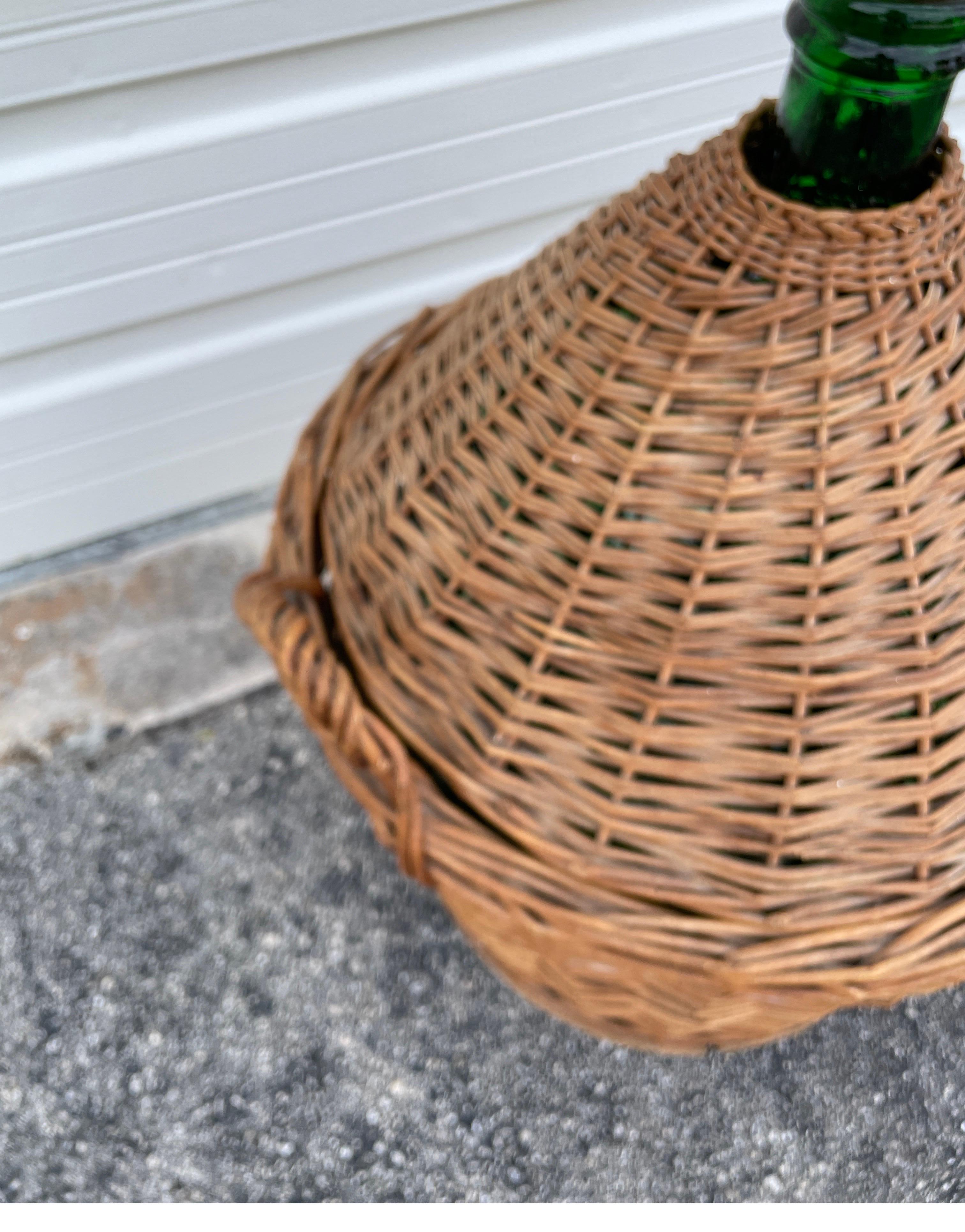 Antica damigiana di vetro verde con il suo cesto di vimini originale, il coperchio e il tappo. Bottiglia dal sorprendente colore verde smeraldo. Il cestino è dotato di maniglie per il trasporto. Se lo si desidera, il Can può essere rimosso dal
