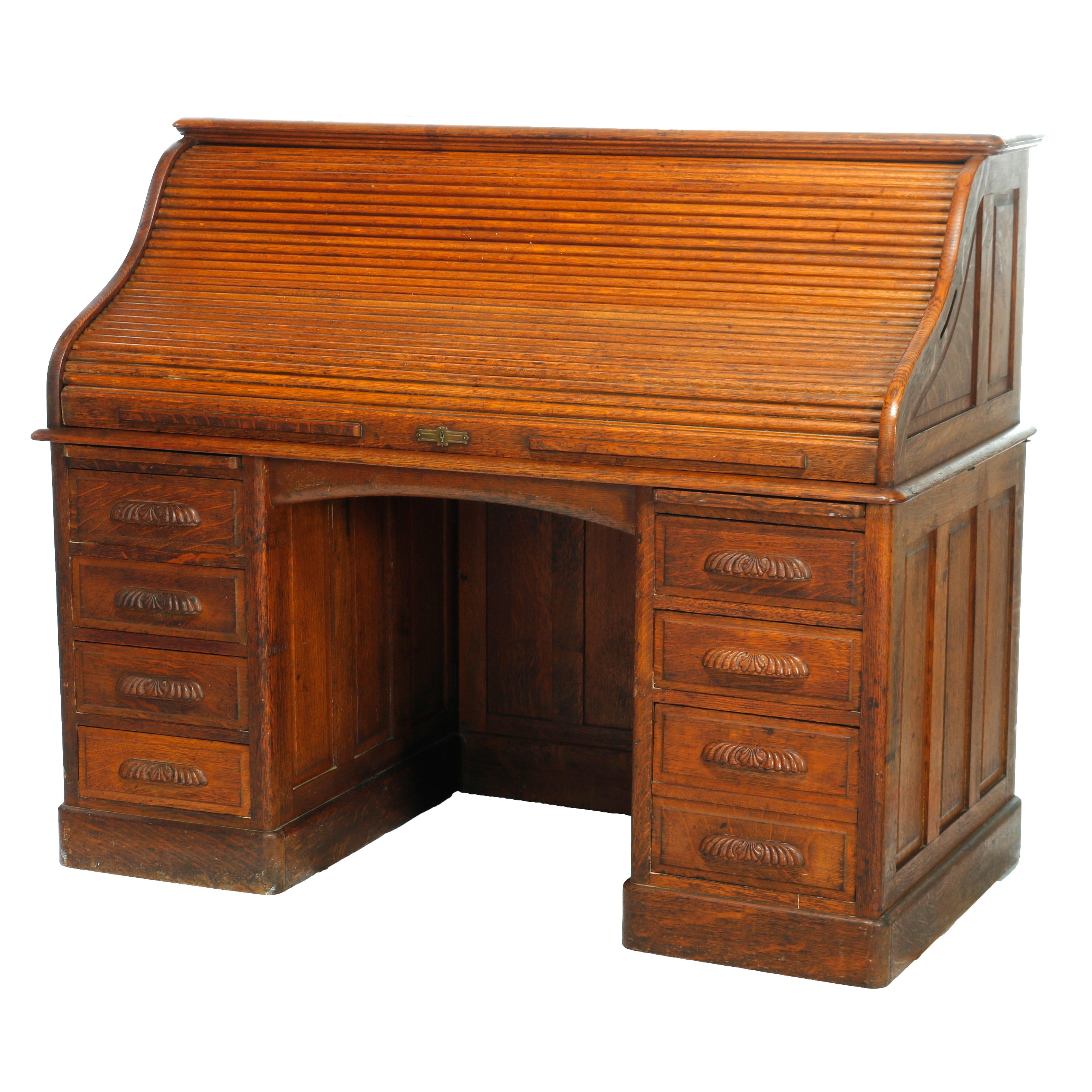 An antique roll top desk offers paneled quarter sawn oak construction with s-top opening to full interior over base with flanking drawer towers having foliate carved pulls and central drawer, c1900

Measures - 50.5'' H X 60'' W X 32'' D.

Catalogue