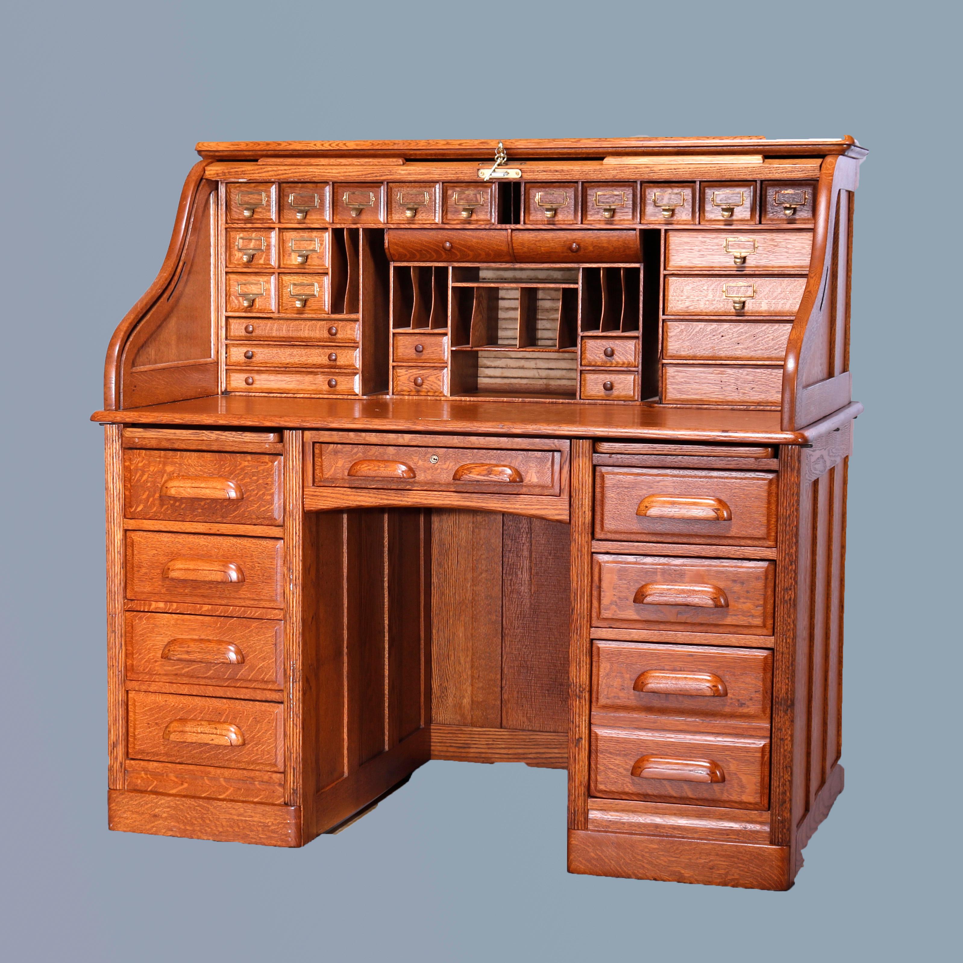 An antique roll top desk in the manner of Derby offers oak construction with s-curve top opening to compartmentalized interior over lower paneled case having two drawer towers flanking central frieze drawer, c1910

Measures - 50.25''H x 50''W x