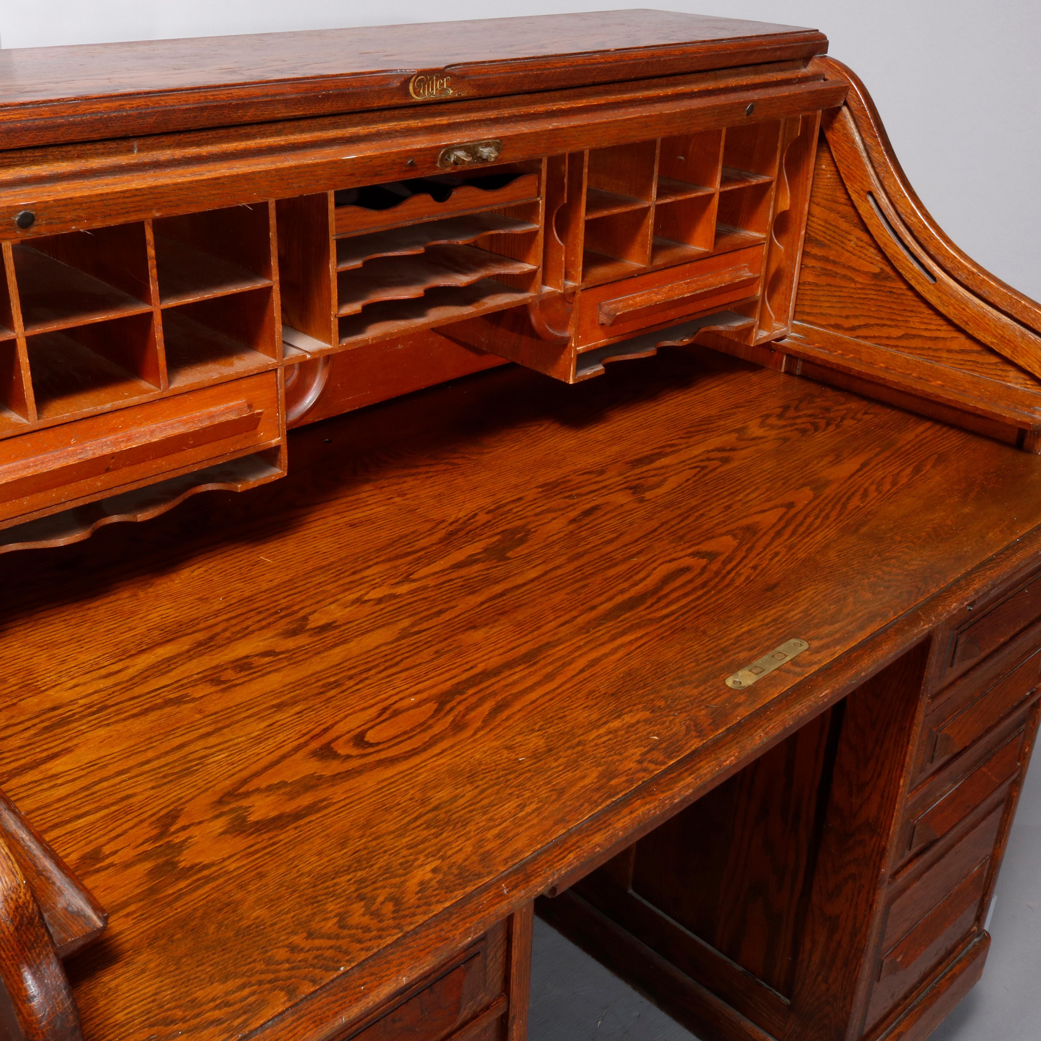 Antique desk by Cutler Desk Factory, Buffalo, NY in the manner of Derby features quarter sawn oak construction with S-form roll top opening to interior pigeon holes and drawers; paneled sides and back; flanking drawer towers, circa
