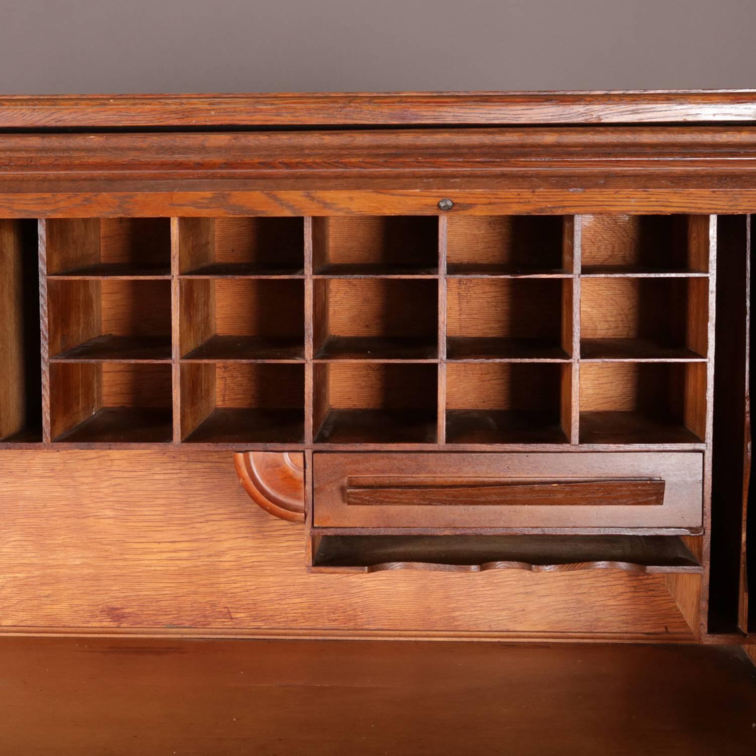 Antique derby school desk by Cutler desk factory, Buffalo, NY features quarter sawn oak construction with s-form roll top opening to interior pigeon holes and drawers; paneled sides and back; flanking drawers; circa 1900.

Measures: 50.5