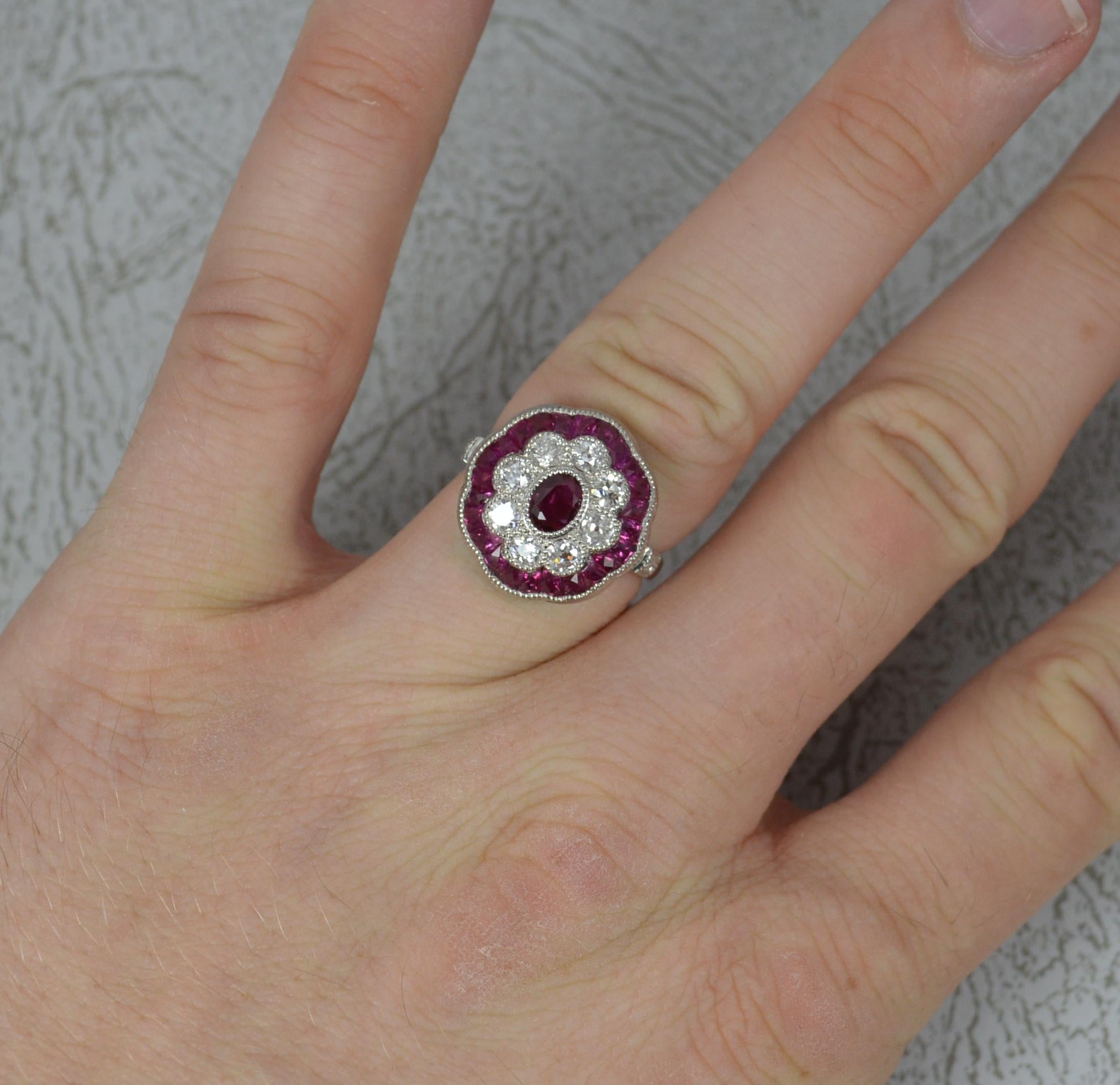 A very striking Ruby and Diamond cluster ring.
Designed with an oval ruby to centre in fine grain bezel setting with eight old European cut diamonds surrounding with fancy calibre, French cut rubies to the edge. 15.4mm x 16.7mm cluster head.
Set