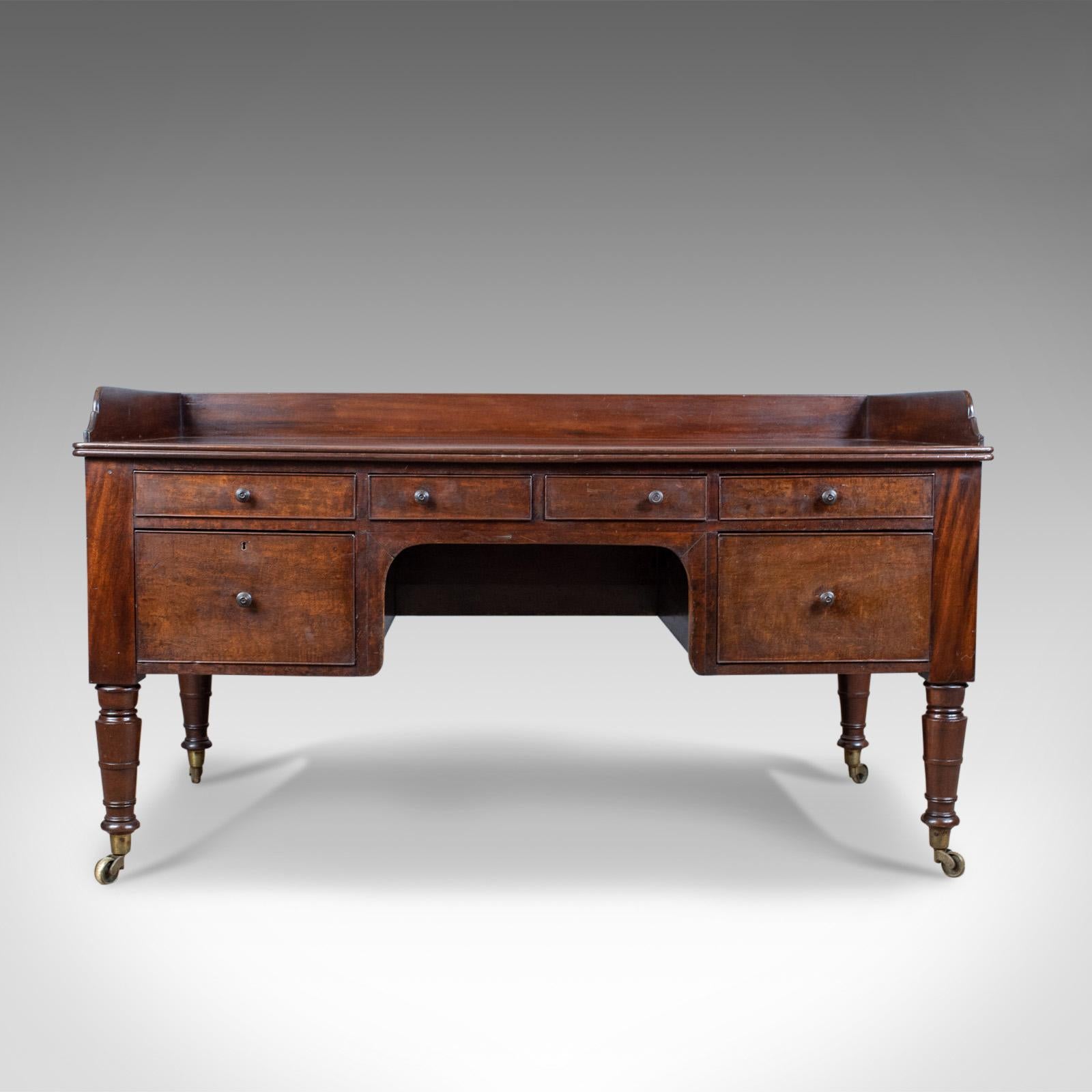 This is an antique desk, a large, English, William IV mahogany kneehole desk dating to the early 19th century, circa 1835.

Of generous proportions offering a large work surface
Shaped, three-quarter up-stand 
Rear overhang for close wall