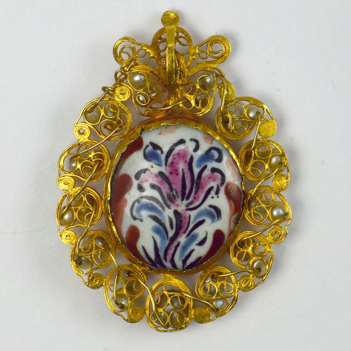 A high karat yellow gold devotional pendant centering a painted enamel of Saint Joseph with a blossoming staff, to the reverse a lily. The enamel surrounded by curliques of high karat yellow gold set with 26 drilled natural pearls. The enamel of