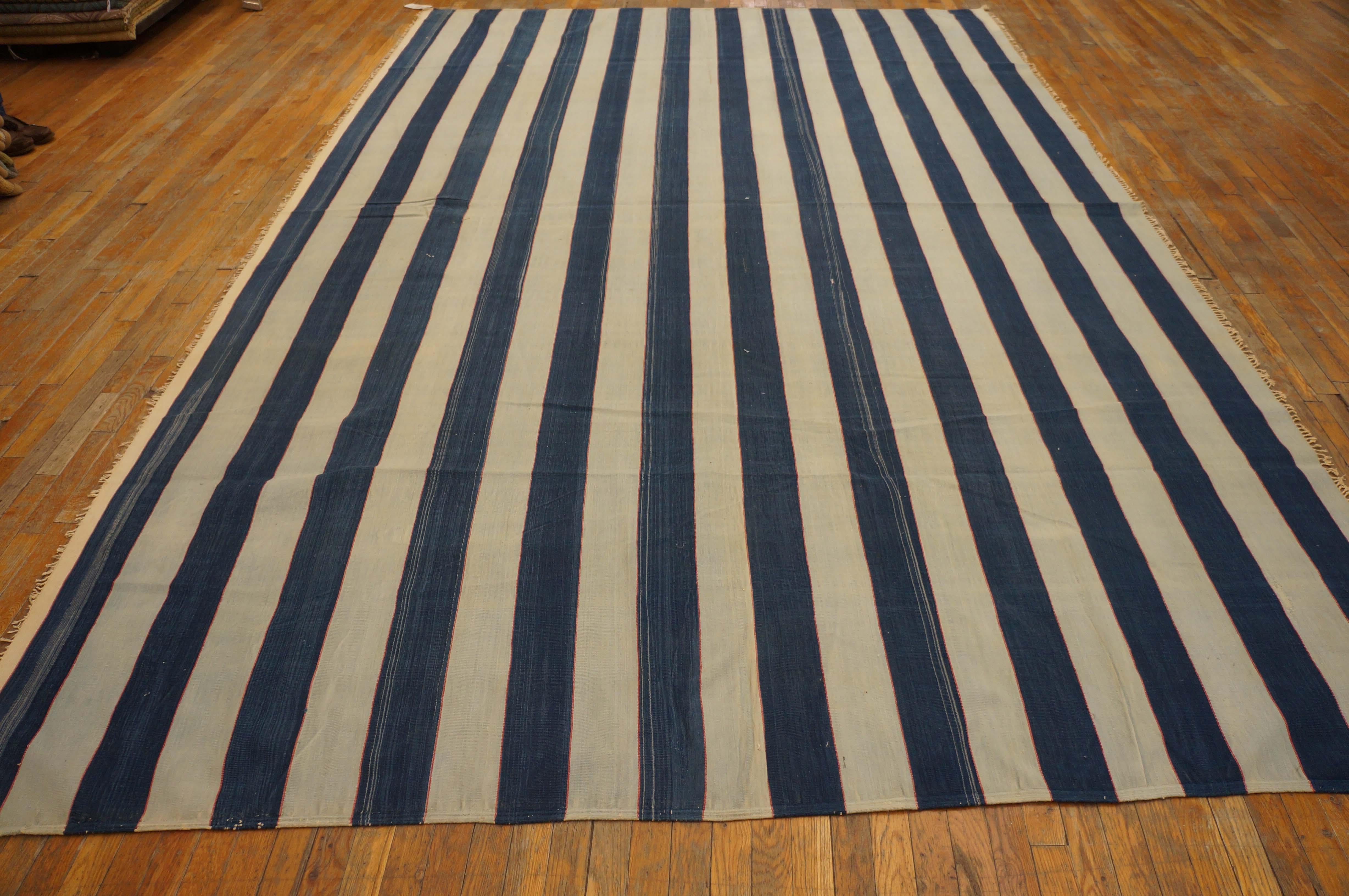 For every 100 dhurries with horizontal stripes, there is one with vertical bands. Here the equal width abrashed denim blue and off-white run end to end and are self-bordered on the sides. This is an antique all-cotton piece with good condition with