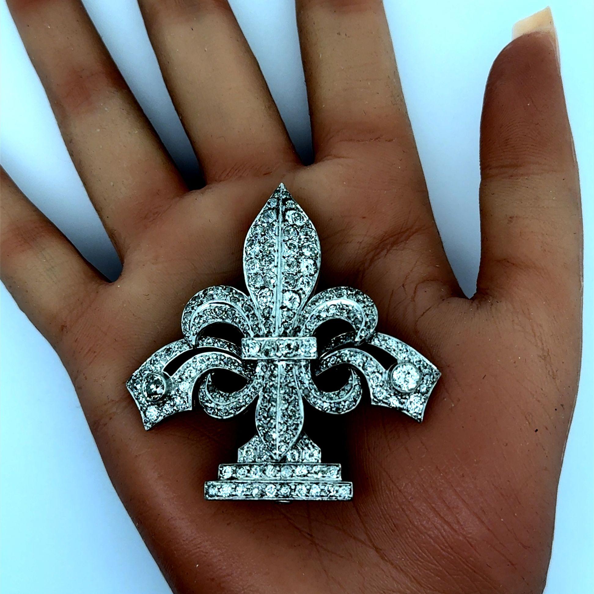 A finely crafted piece of jewelry designed in the Victoria era during the end of the 19th century. It features approximately 9 carats of Old Mine-cut diamonds set in a detailed fleur-de-lis motif. The piece is adorned with intricate curves and