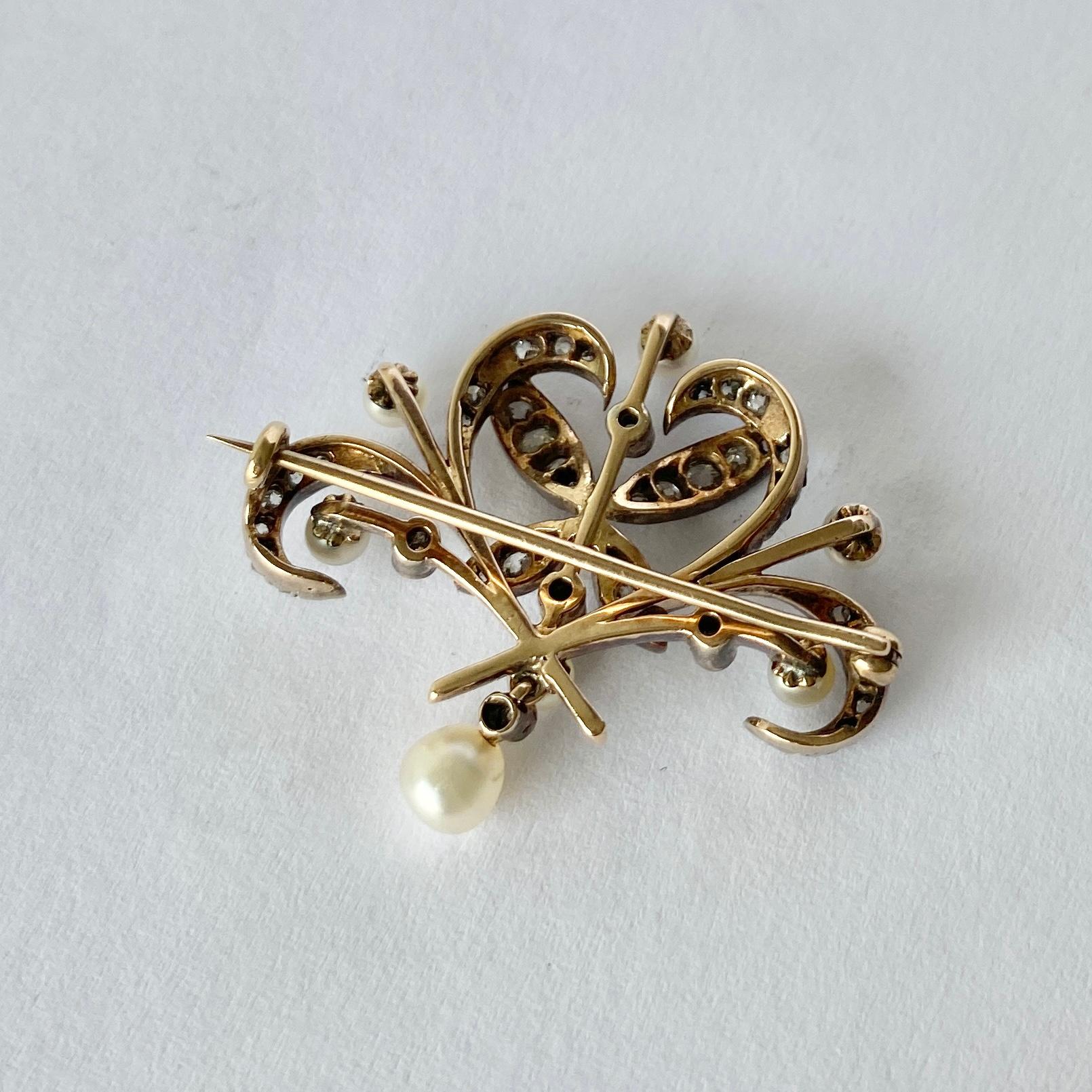 This intricate brooch holds sparkling diamonds and soft shimmery pearls. The stones are all set in platinum and the rest of the brooch is modelled in ??ct gold. The total carat weight of the diamonds is approx 85pts. Comes with box. 

Brooch