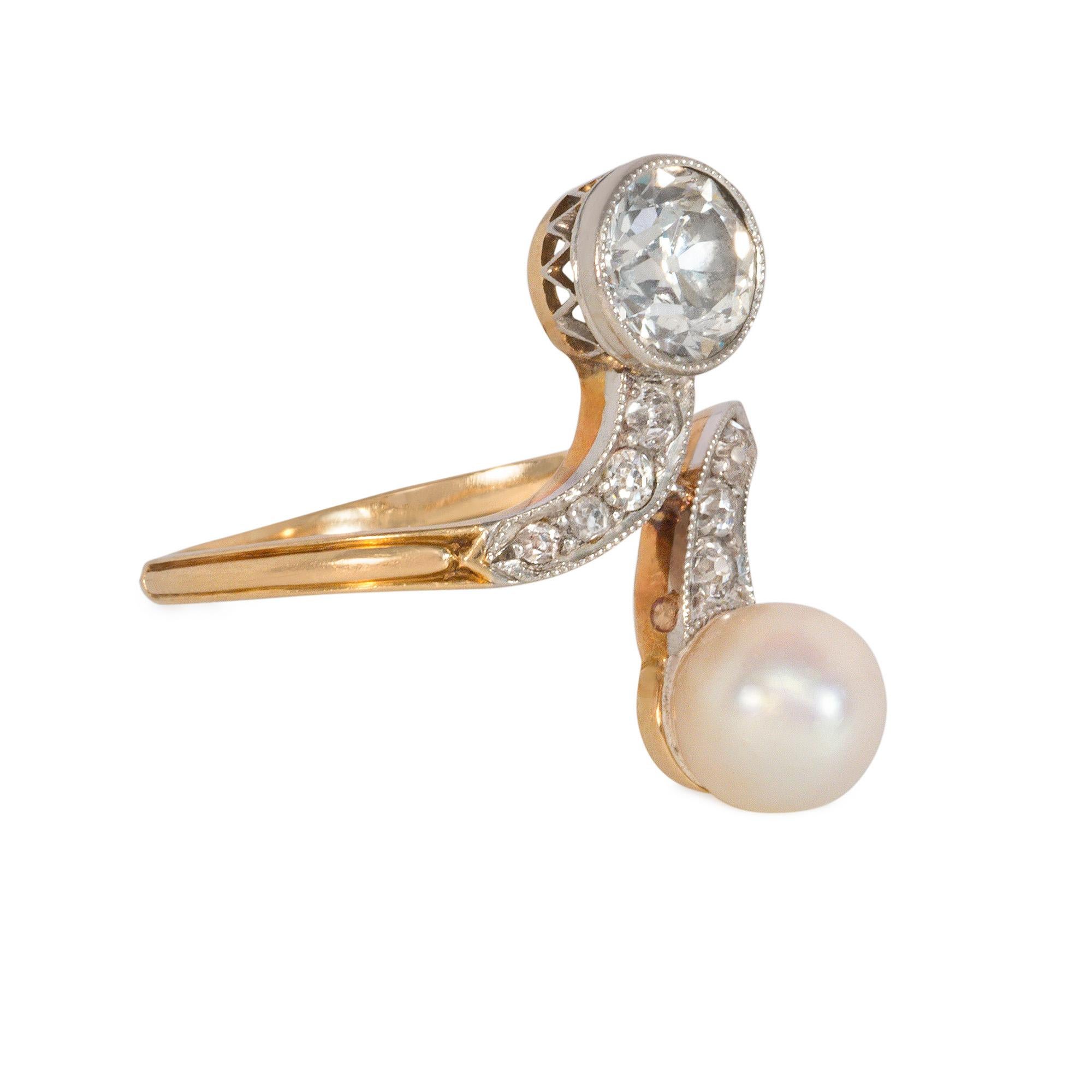 An Edwardian diamond Toi et Moi ring of bypass design set with diamonds and a pearl, in platinum and 18k gold.  Atw 1.10 ct.  Face-up vertical measurement from diamond to pearl: 21mm

Current ring size: US 6.5; please contact us with re-sizing