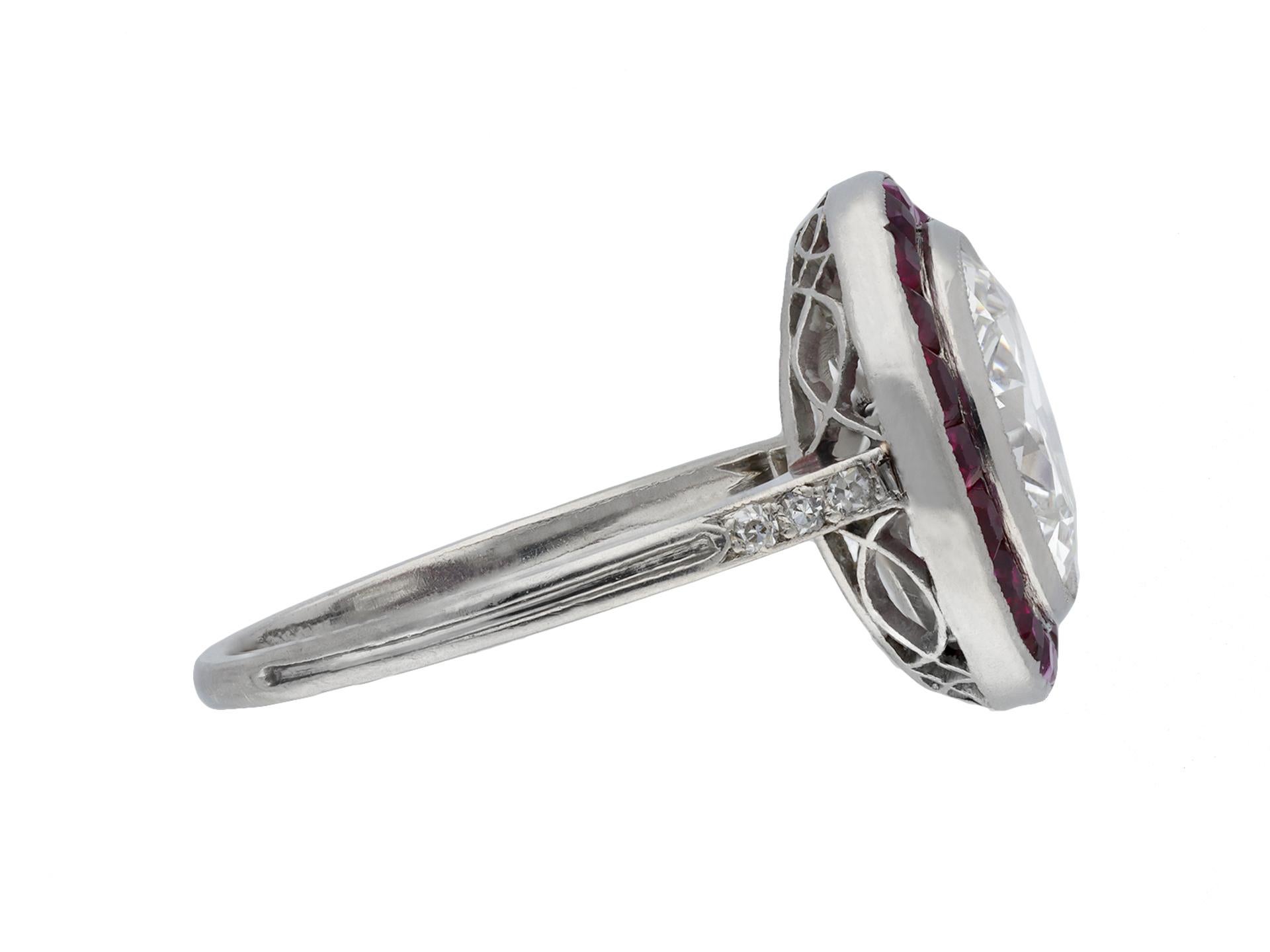 Antique diamond and ruby target ring. Centrally set with a round transitional cut diamond, F colour, VS1 clarity with an approximate weight of 2.46 carats, in an open back rubover settting, encircled by a single row of twenty tapered baguette cut