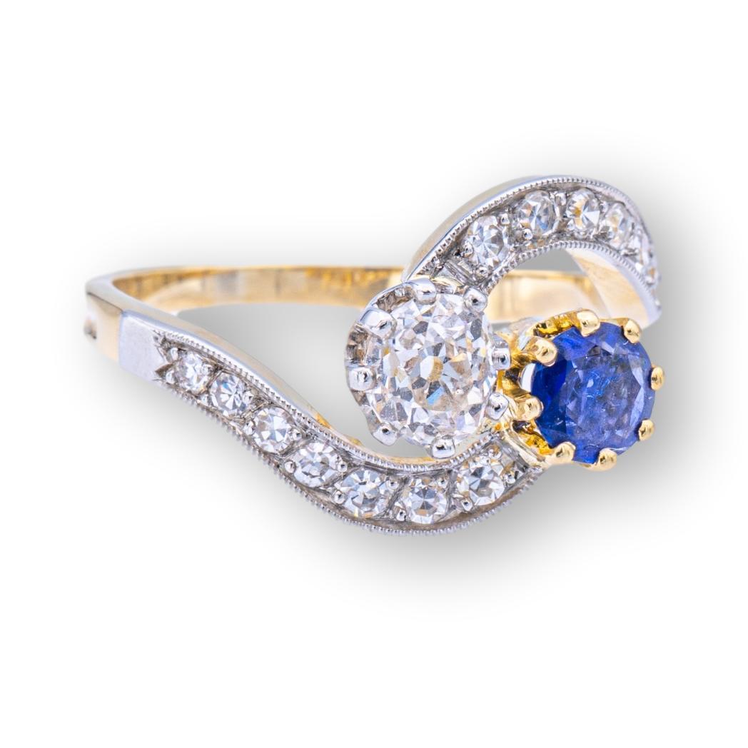 Antique French sapphire and diamond bypass ring finely crafted in 18K yellow gold and platinum set with one old-mine cut diamond weighing 0.35 cts approximately in an I - J color beautiful eye clean stone, and one deep blue sapphire weighing 0.35