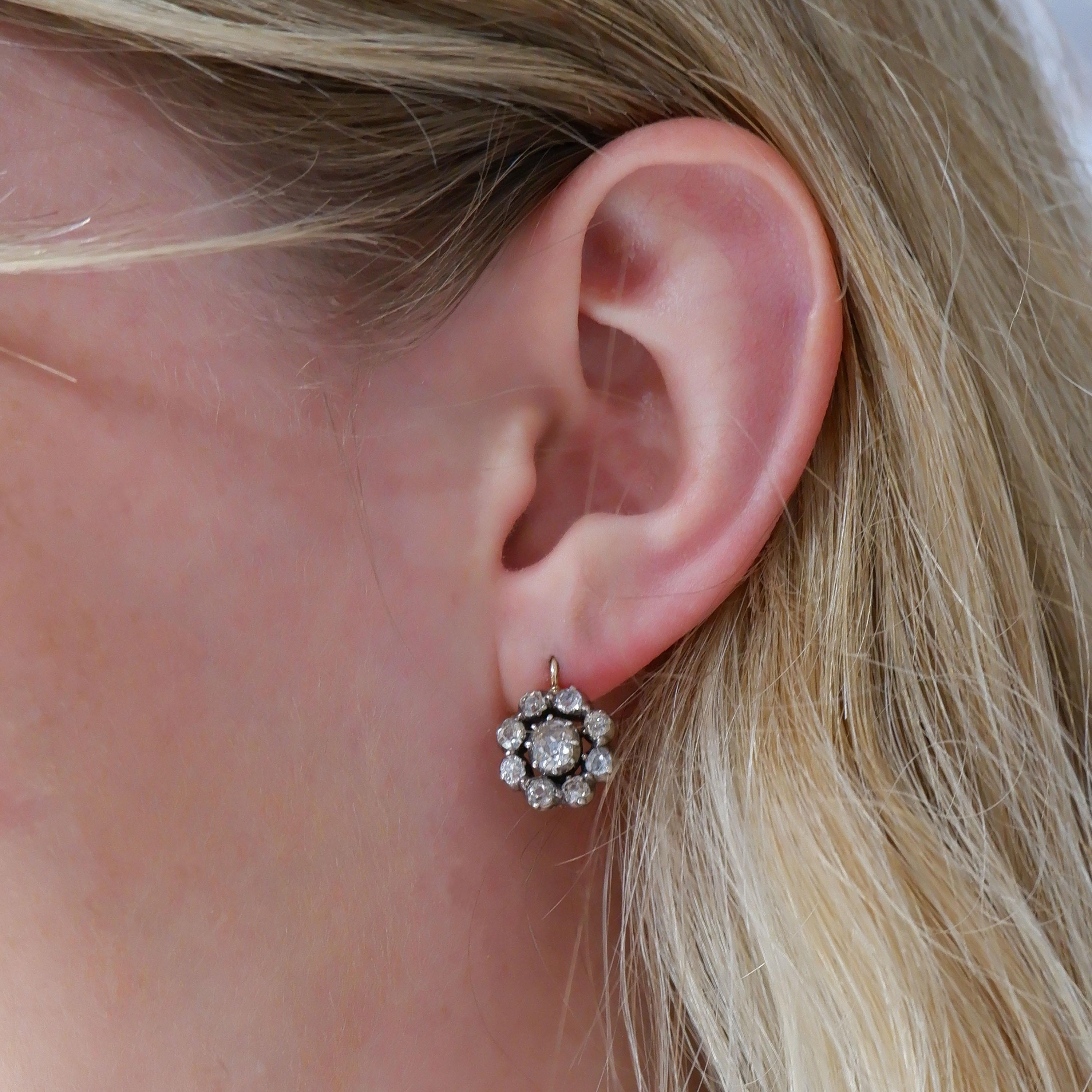 A pair of antique diamond cluster earrings, set with old-cut diamonds, in cut down settings, mounted in silver-upon-gold, on wire fittings with later safety clips, circa 1880, with an approximate total weight of 4.50 carats.

Length including wires