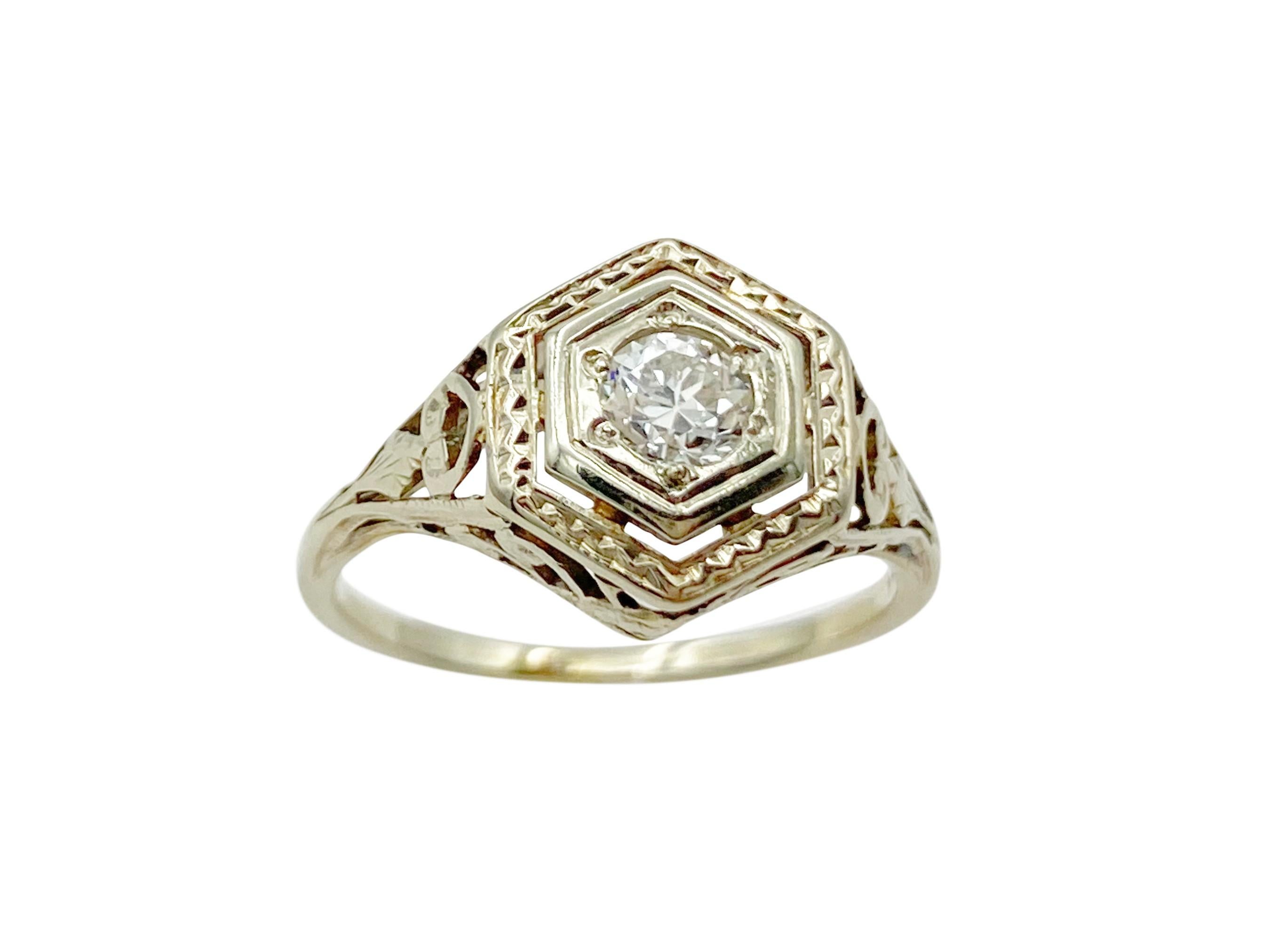 Lovely antique Art Deco ring circa the 1920s. The 14k white gold face has a unique hexagonal shape with a 3.6mm Old European cut white diamond nestled in the center. The hand-worked ring features openwork filigree, milgrain and engraved