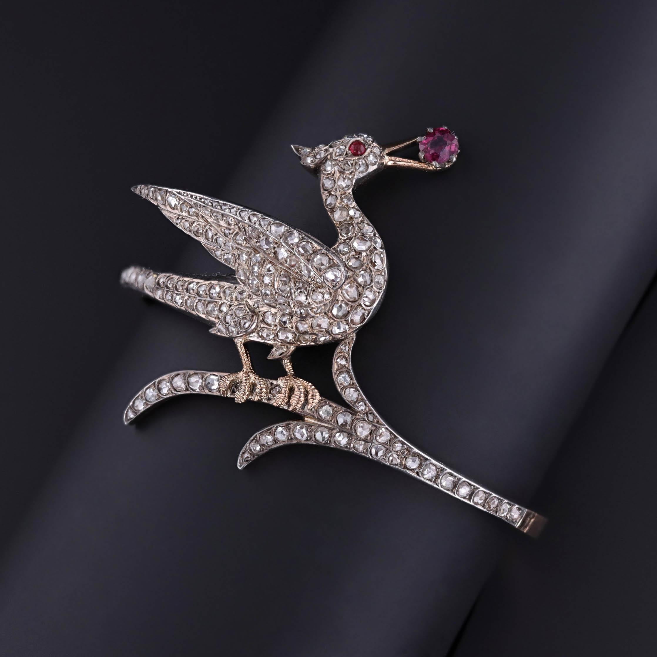 Questo bracciale bangle antico (circa 1880-1900) presenta un uccello con un rubino naturale rosso porpora vivido incastonato nel becco e un occhio in pasta di vetro al piombo, incastonato in argento al 98% e oro 18k. L'uccello è ornato da 157