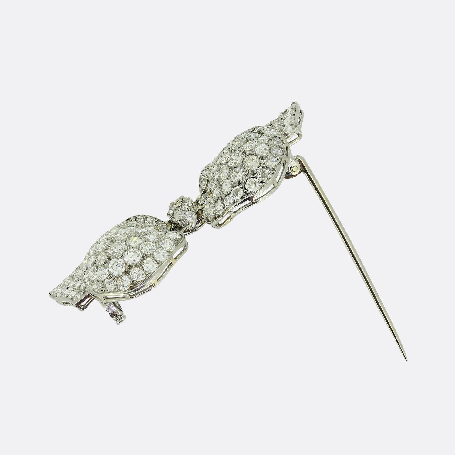 Here we have an antique diamond brooch that dates back to the Edwardian era. The piece features a double bowed ribbon style frame with a knot at the centre which has been pavé set with a vast array of round faceted old European cut diamonds. All