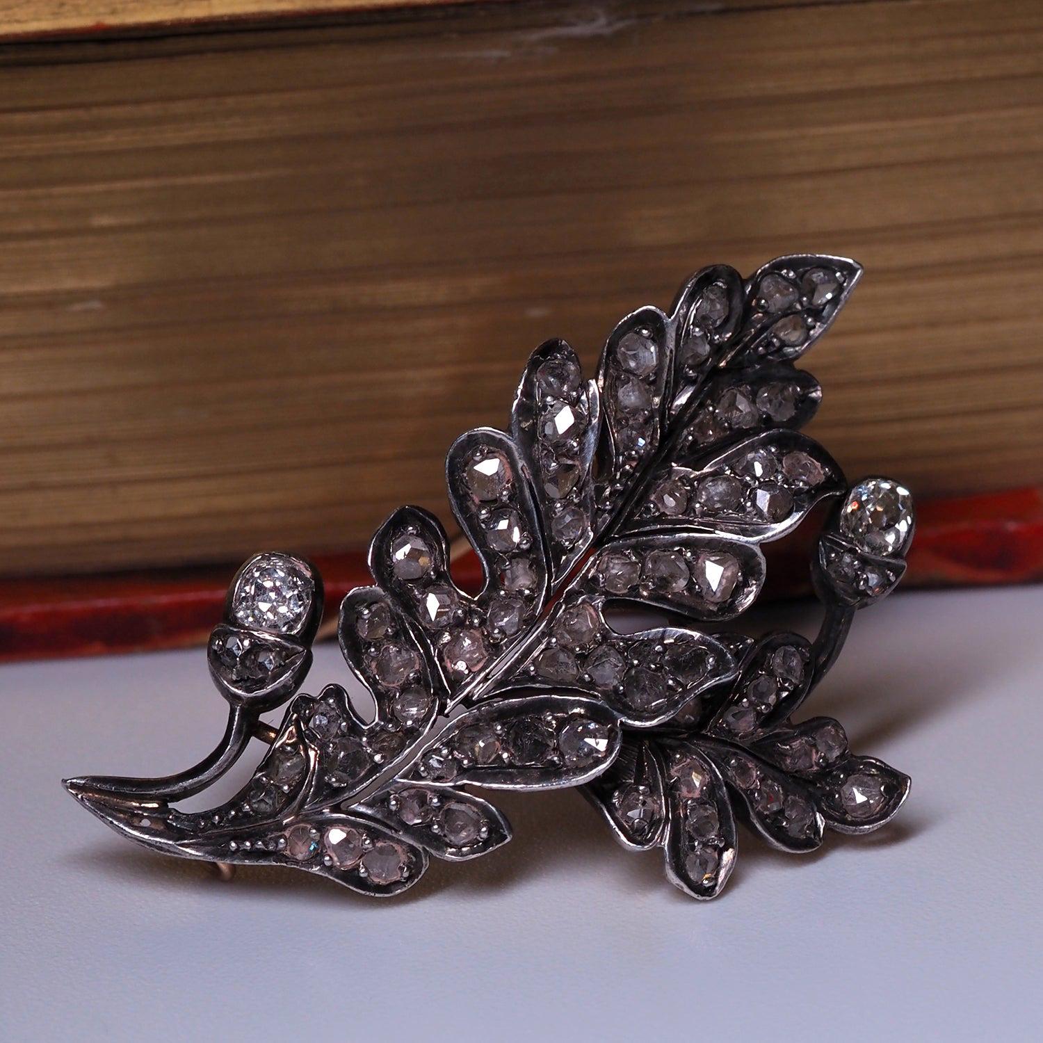 A mid-Victorian diamond oak leaf brooch, circa 1860s. Set in yellow gold and silver, with a brilliant cut diamonds, length 45 mm

Designed as a cluster of two oak leaves, of graduated size and pave set with old cushion cut diamonds, a stem below set