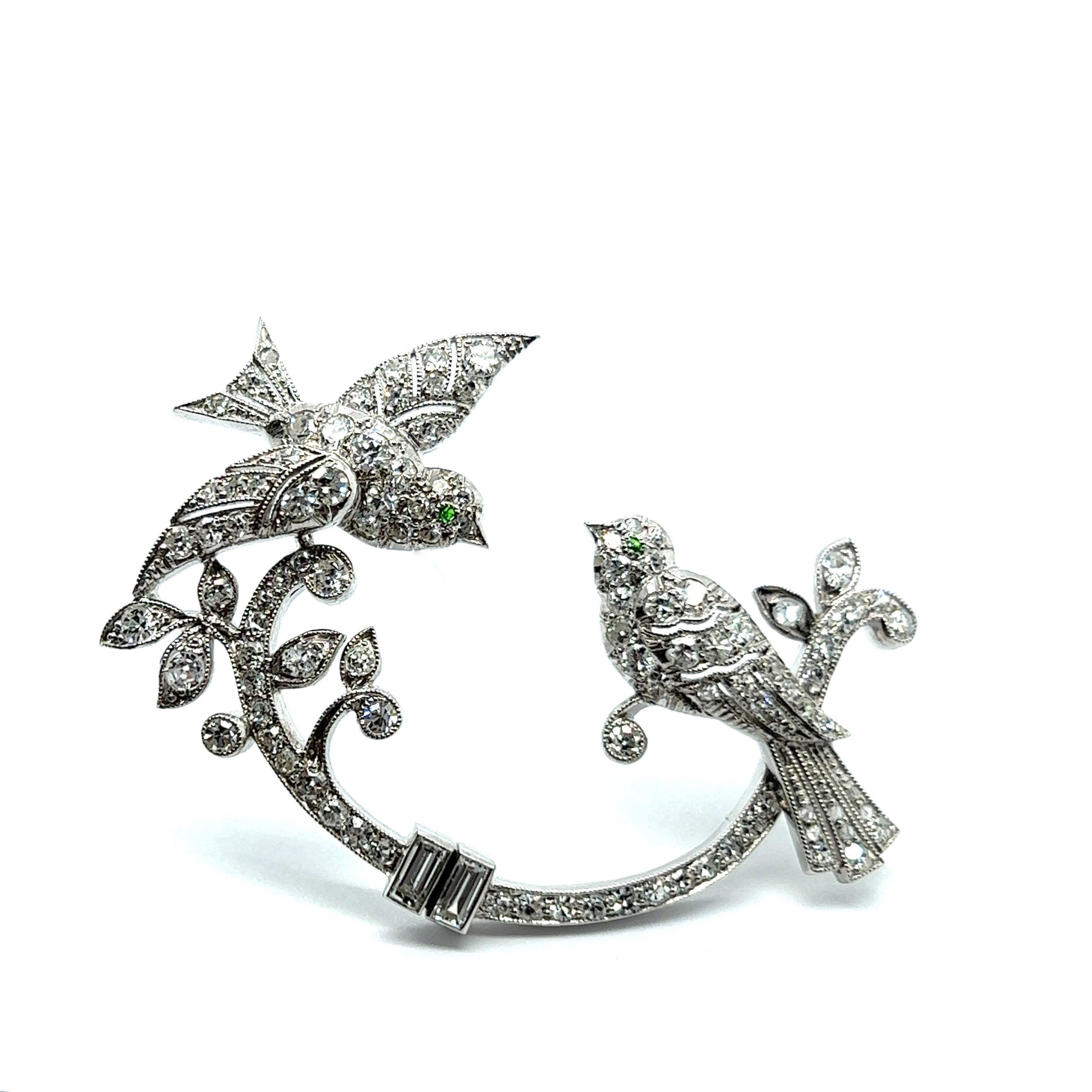 Exquisite antique brooch with diamonds steeped in history and rich symbolism. This captivating piece highlights a motif of two lifelike birds gracefully perched on a beautifully rendered branch. The symbolism of birds in jewelry dates back